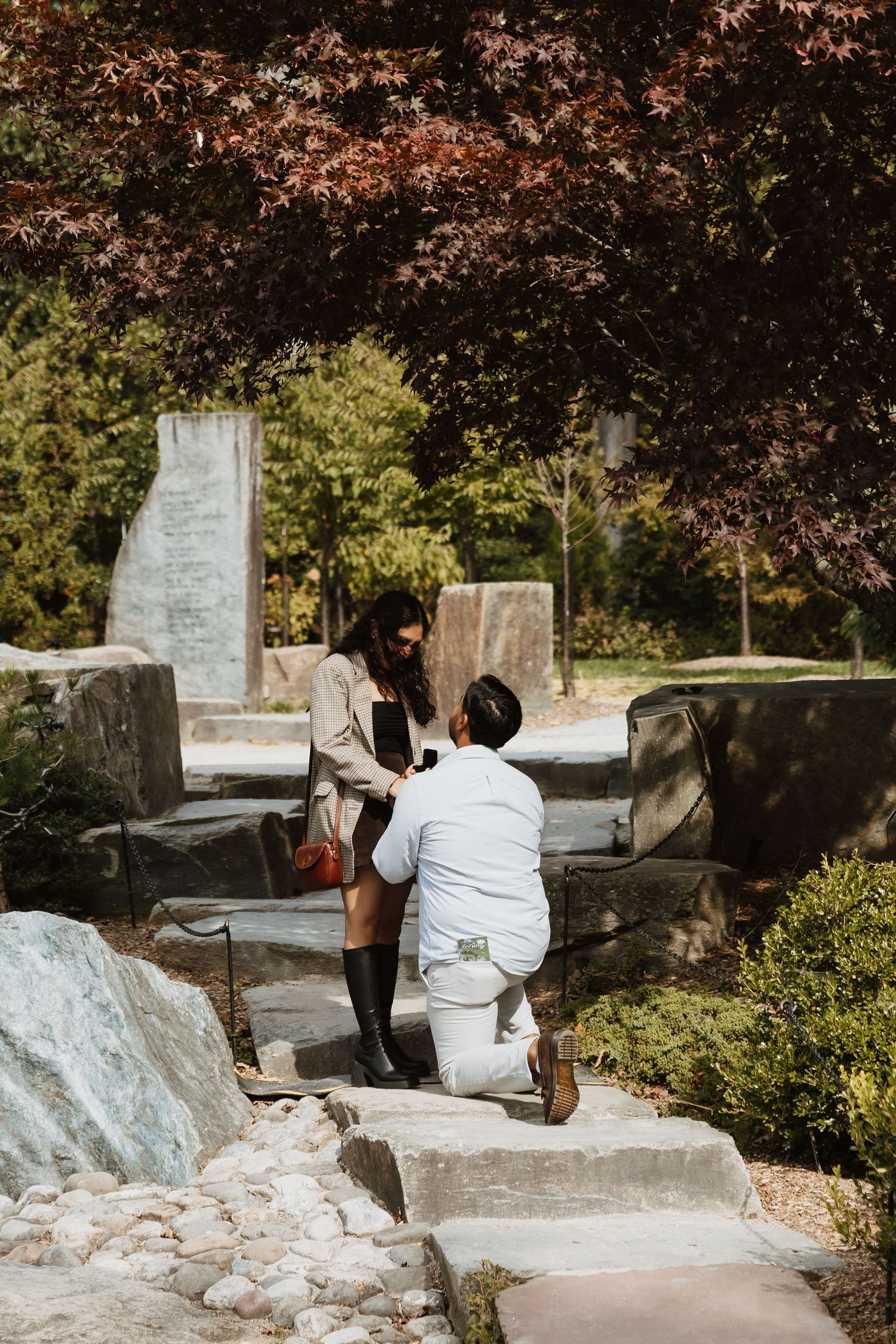 People work together to carve inscriptions into a stone memorial or monument in an outdoor setting.
