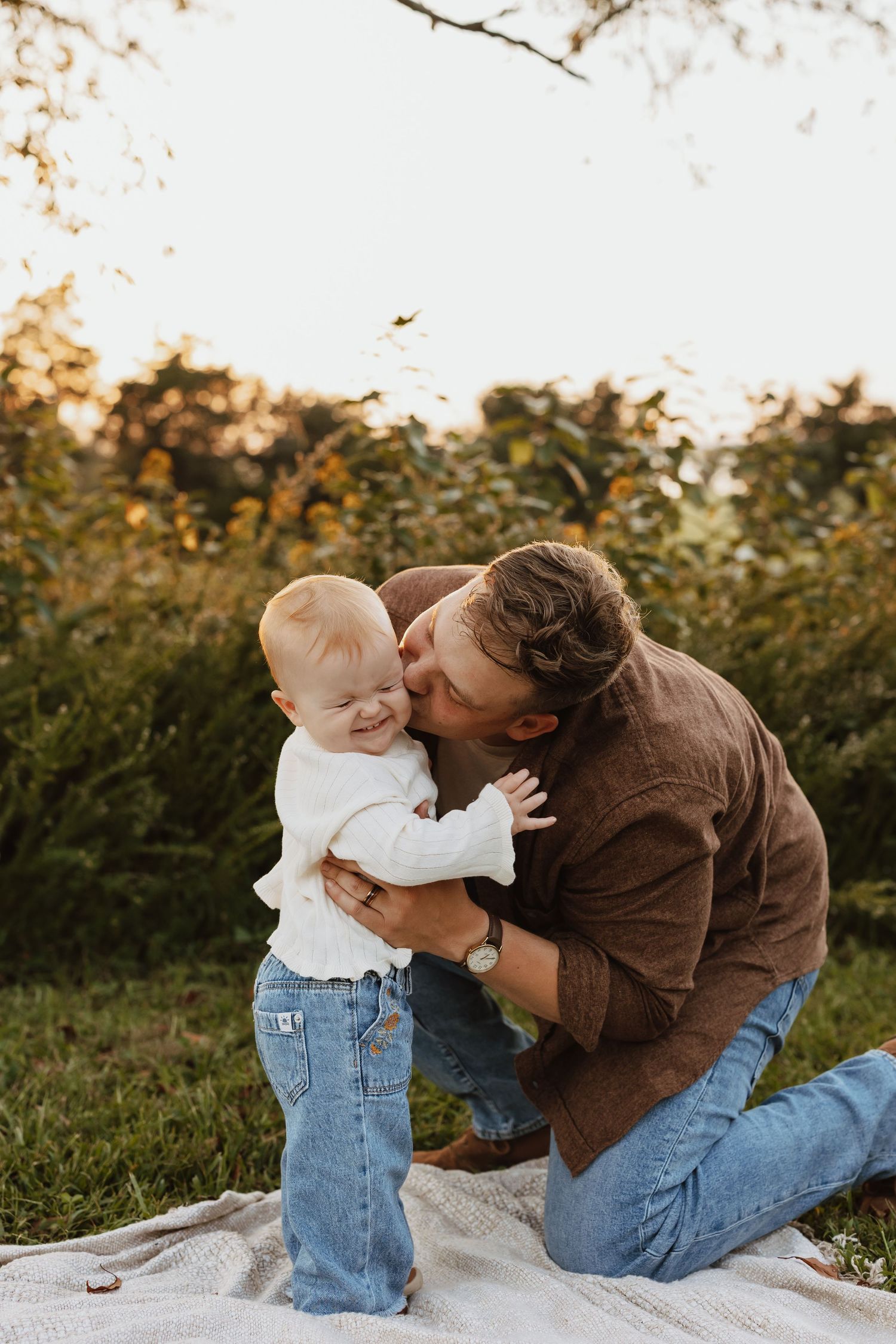 A tender moment between parent and child sitting on a blanket outdoors during golden hour.