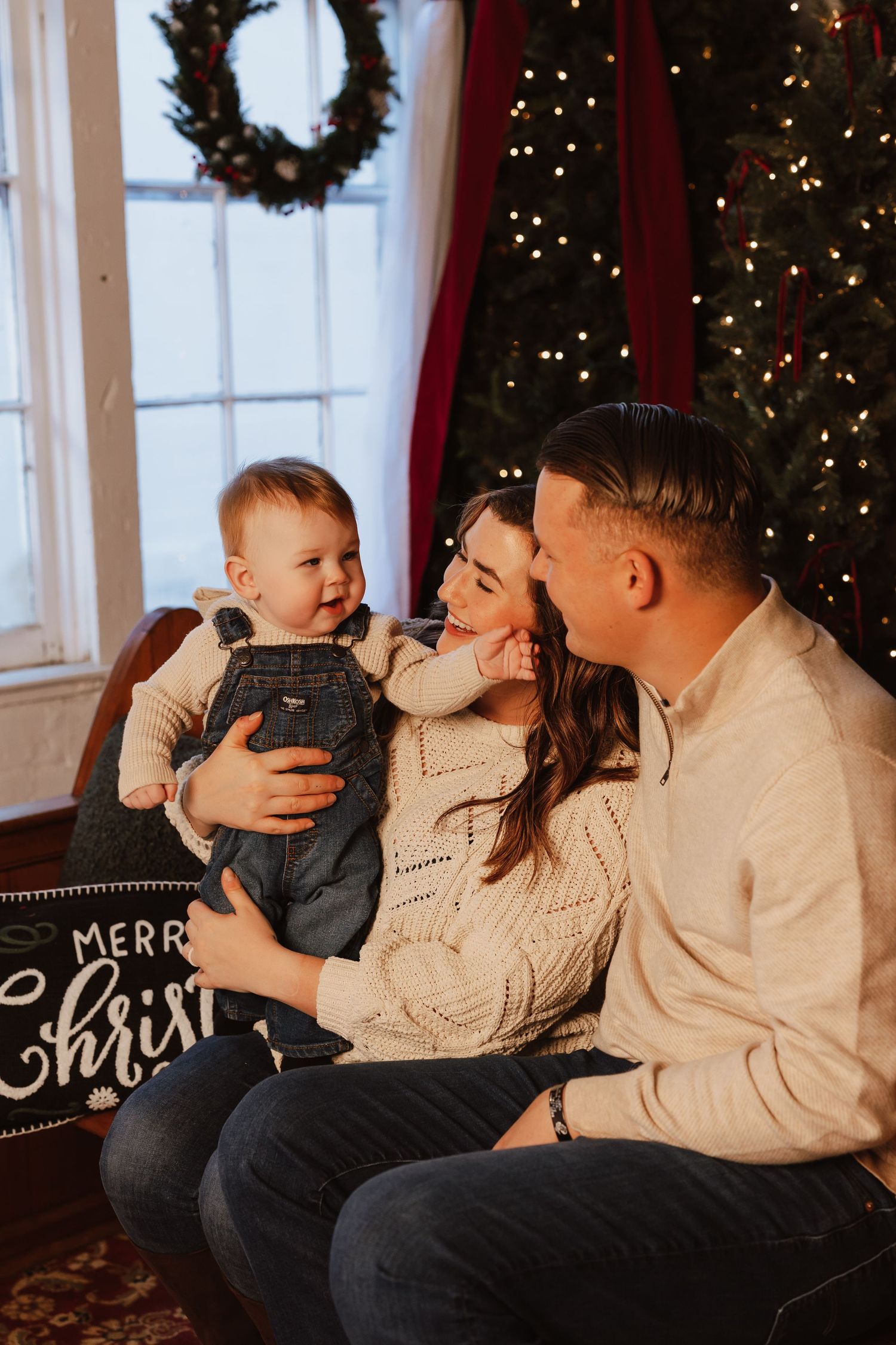 A family shares a joyful moment together in front of a Christmas tree with twinkling lights and holiday decor.