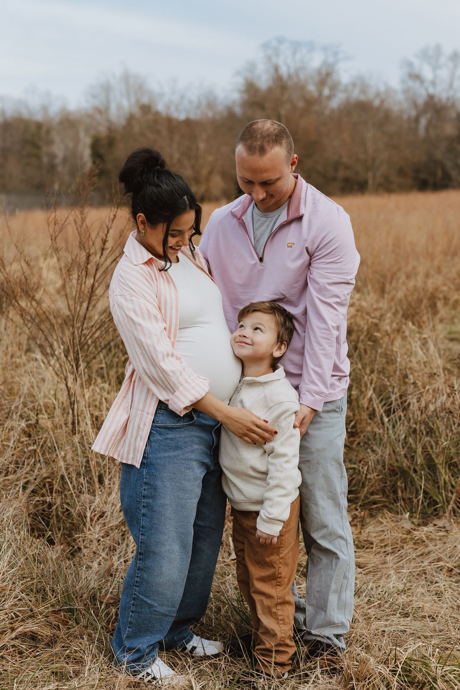 Family shares tender moments together in a golden autumn field during outdoor photo session.