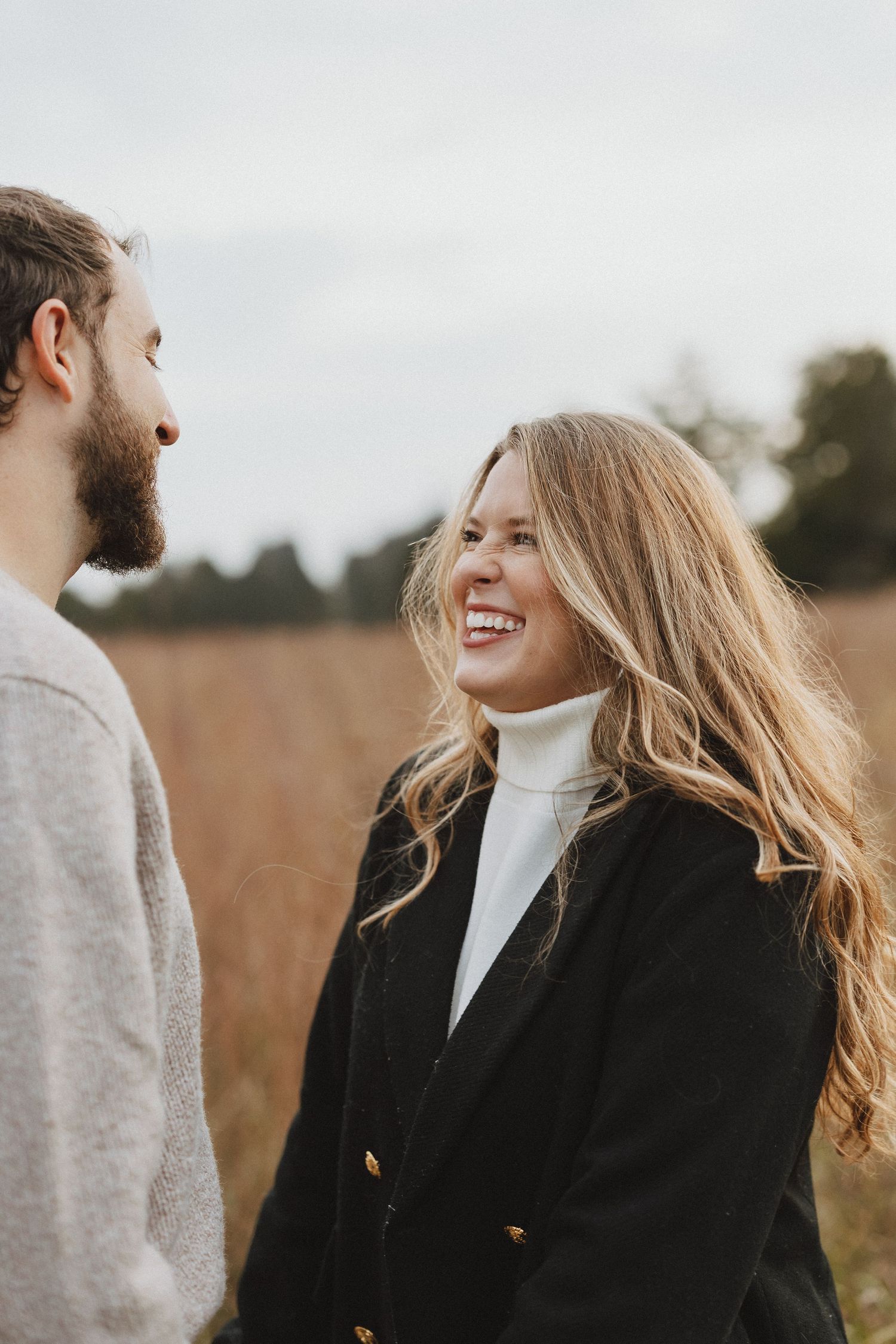 A couple shares a joyful moment together in a golden field on an autumn day.