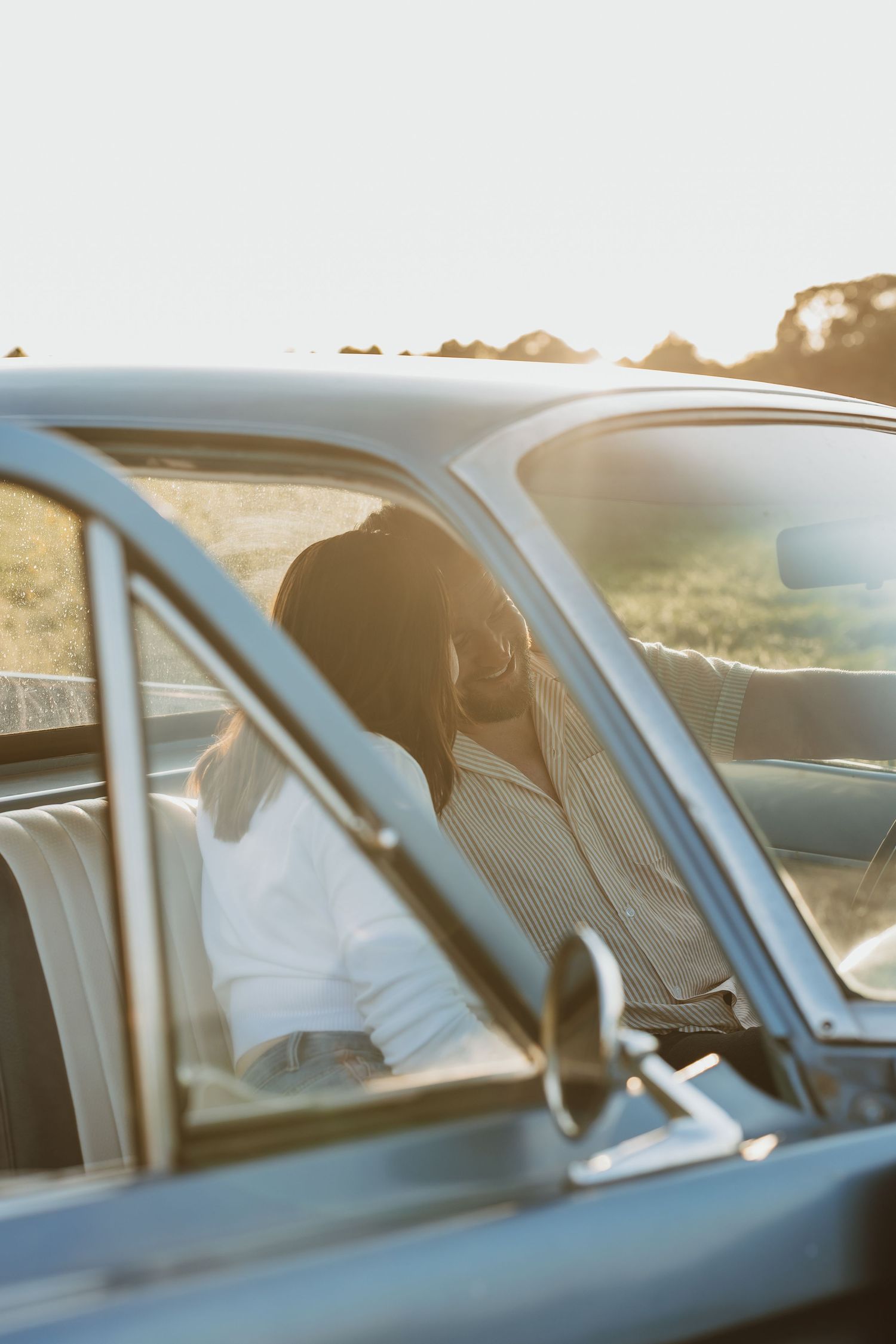 A vintage car with sunlit interior parked on a scenic road during golden hour.