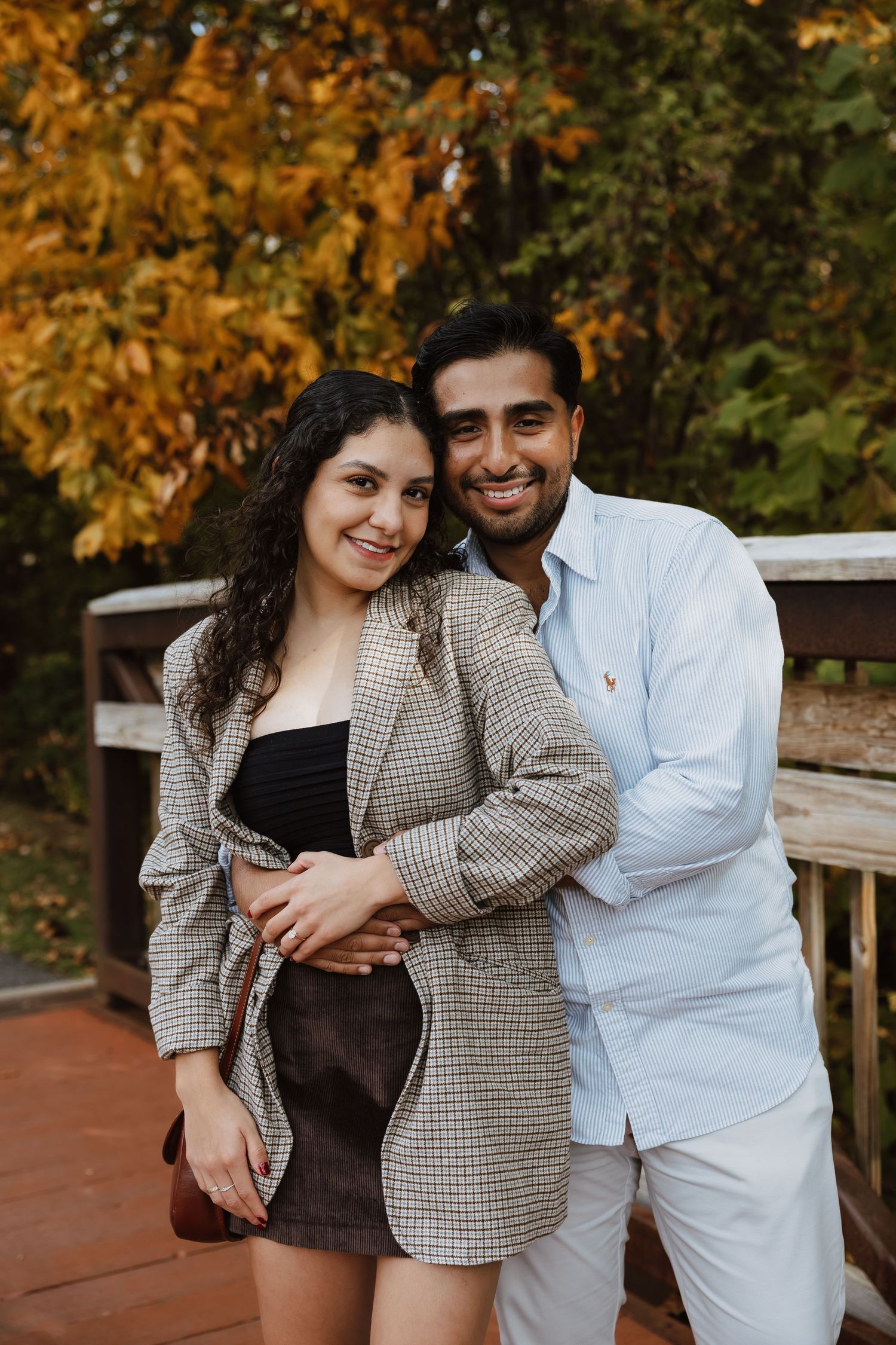 Romantic autumn photoshoot with couple embracing outdoors against backdrop of golden fall foliage.