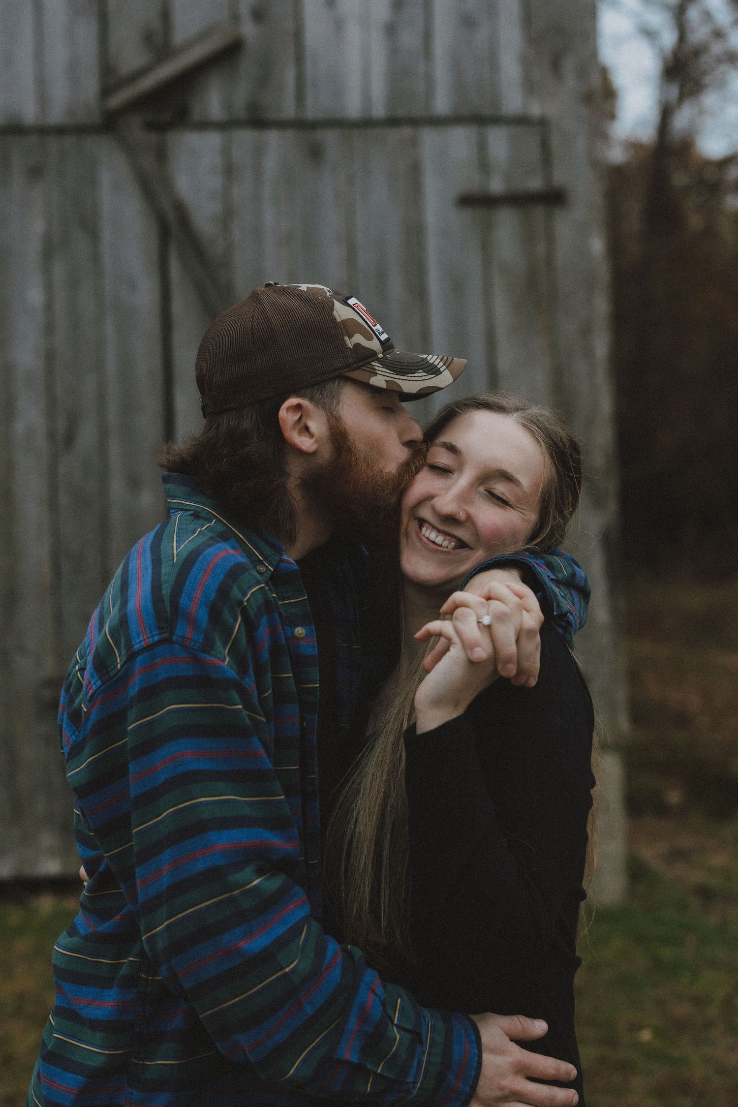 A couple shares a tender moment outdoors against a wooden fence background in a series of candid shots.