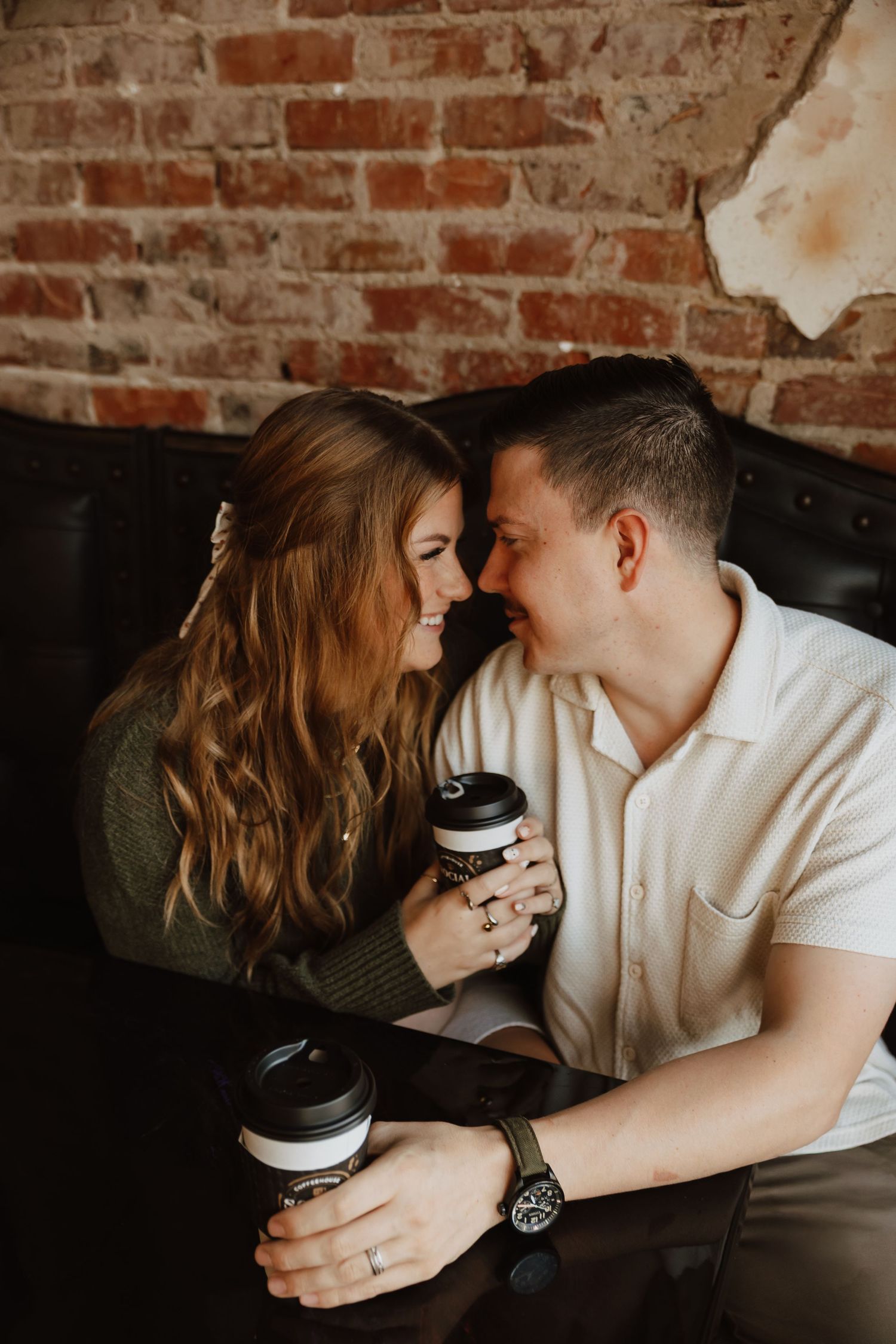 Intimate coffee date scene against brick wall background with couple sharing tender moments.