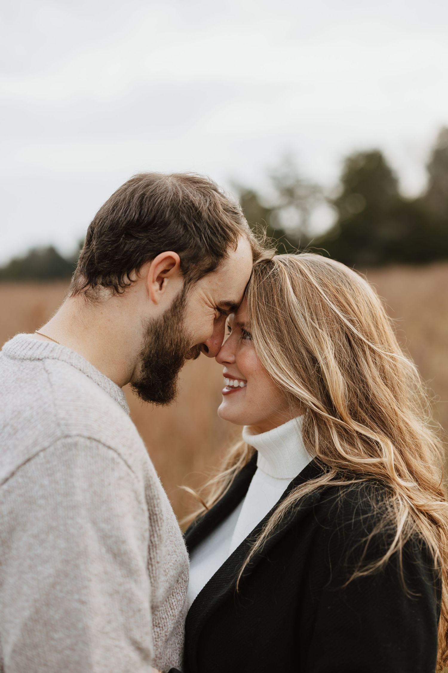Romantic outdoor photoshoot scene showing intimate moments between couple in grey and black attire.