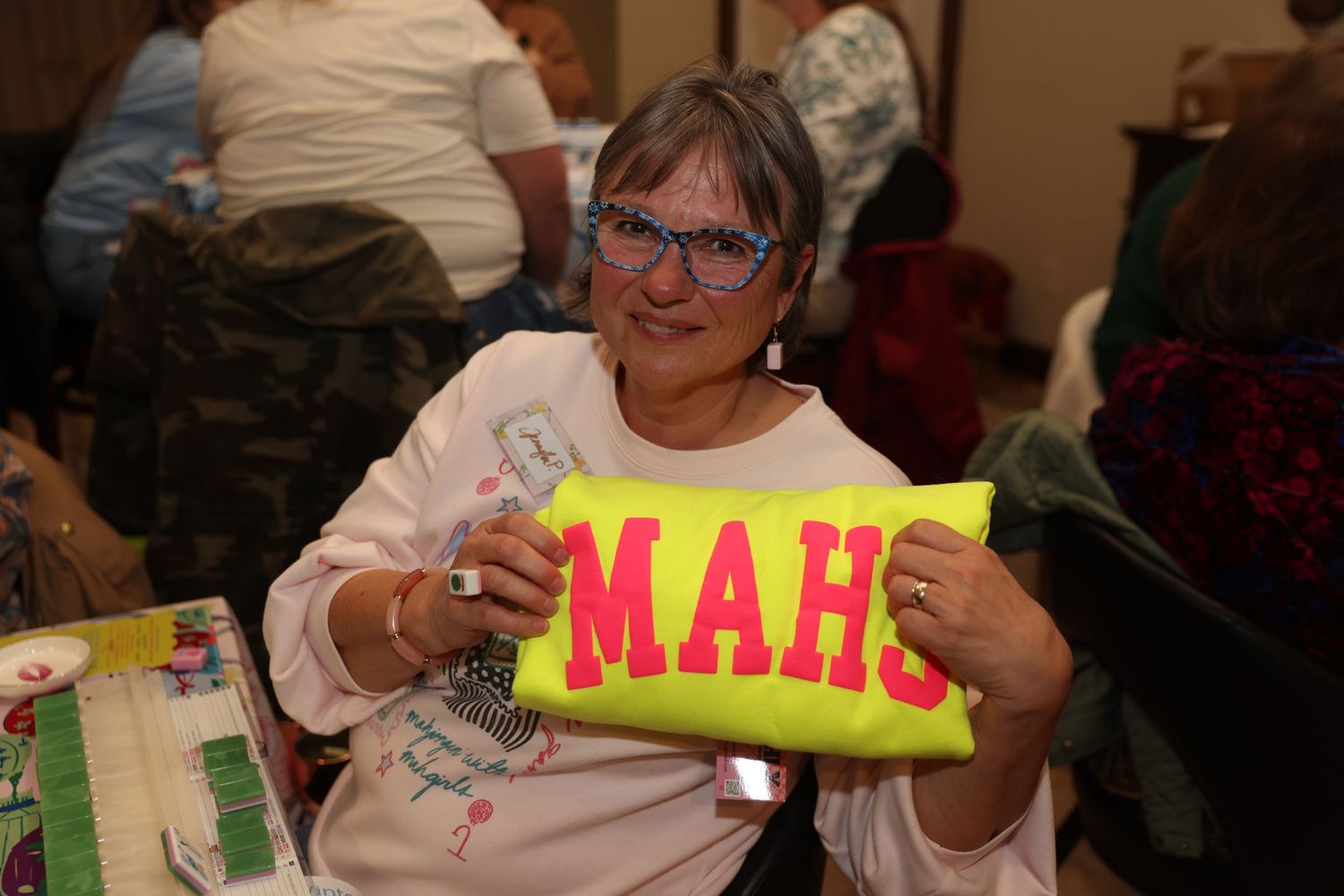 A group of seniors participate in a recreational activity holding up colorful letter signs at a community center.