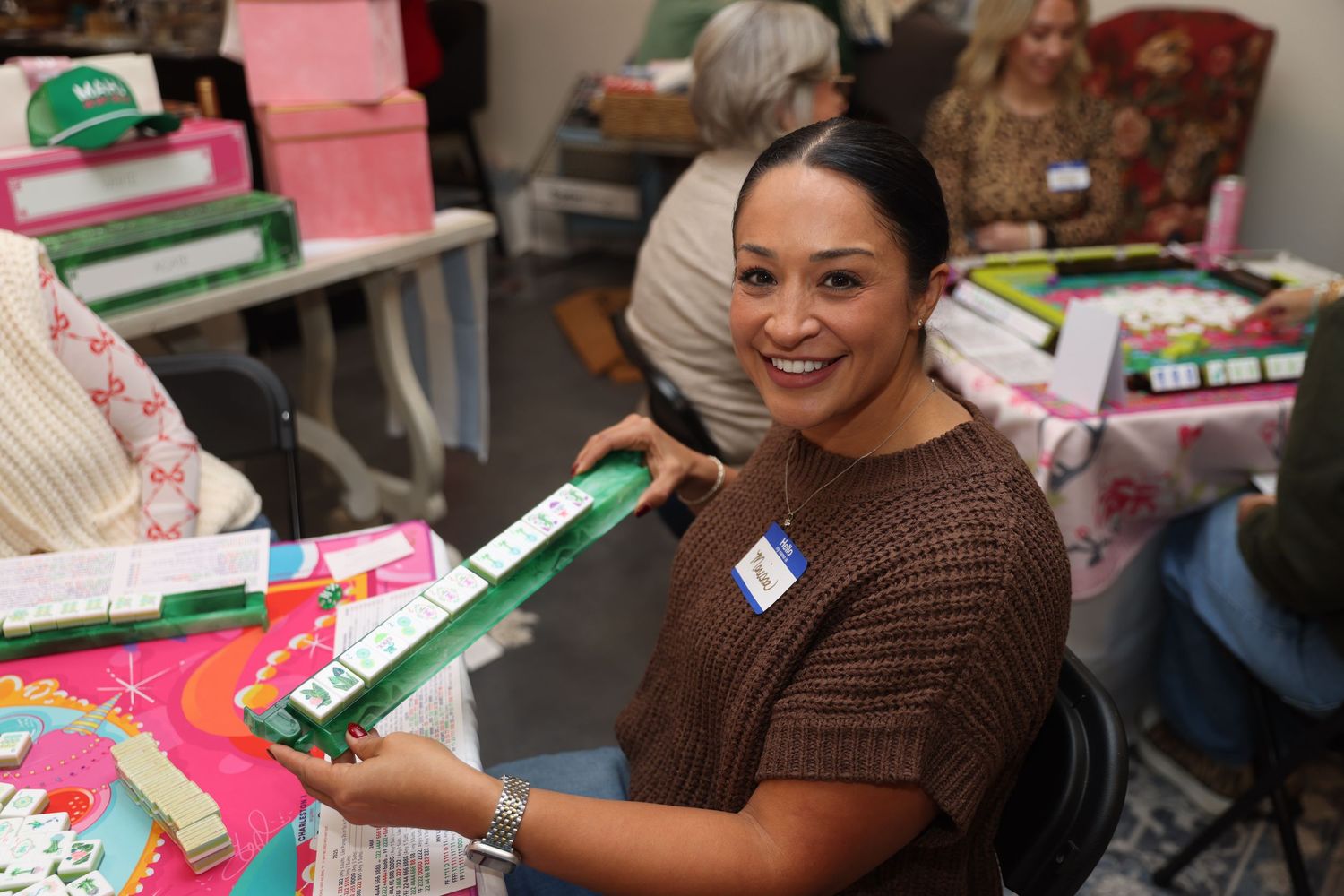 A volunteer smiles while sorting through holiday gift boxes and donations at a charitable organization.