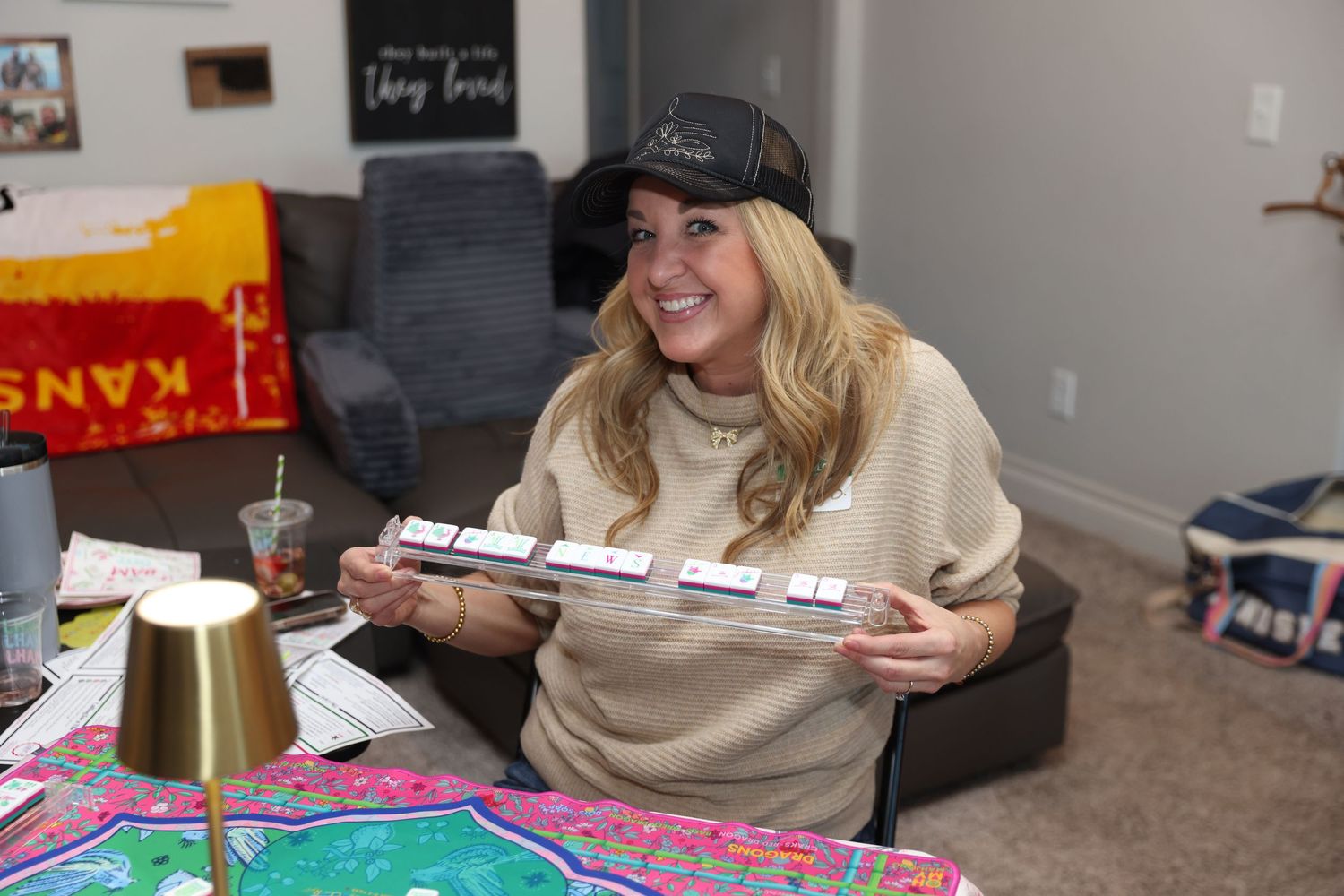 Someone wearing a baseball cap and beige sweater holds a model airplane while sitting at a colorful table.