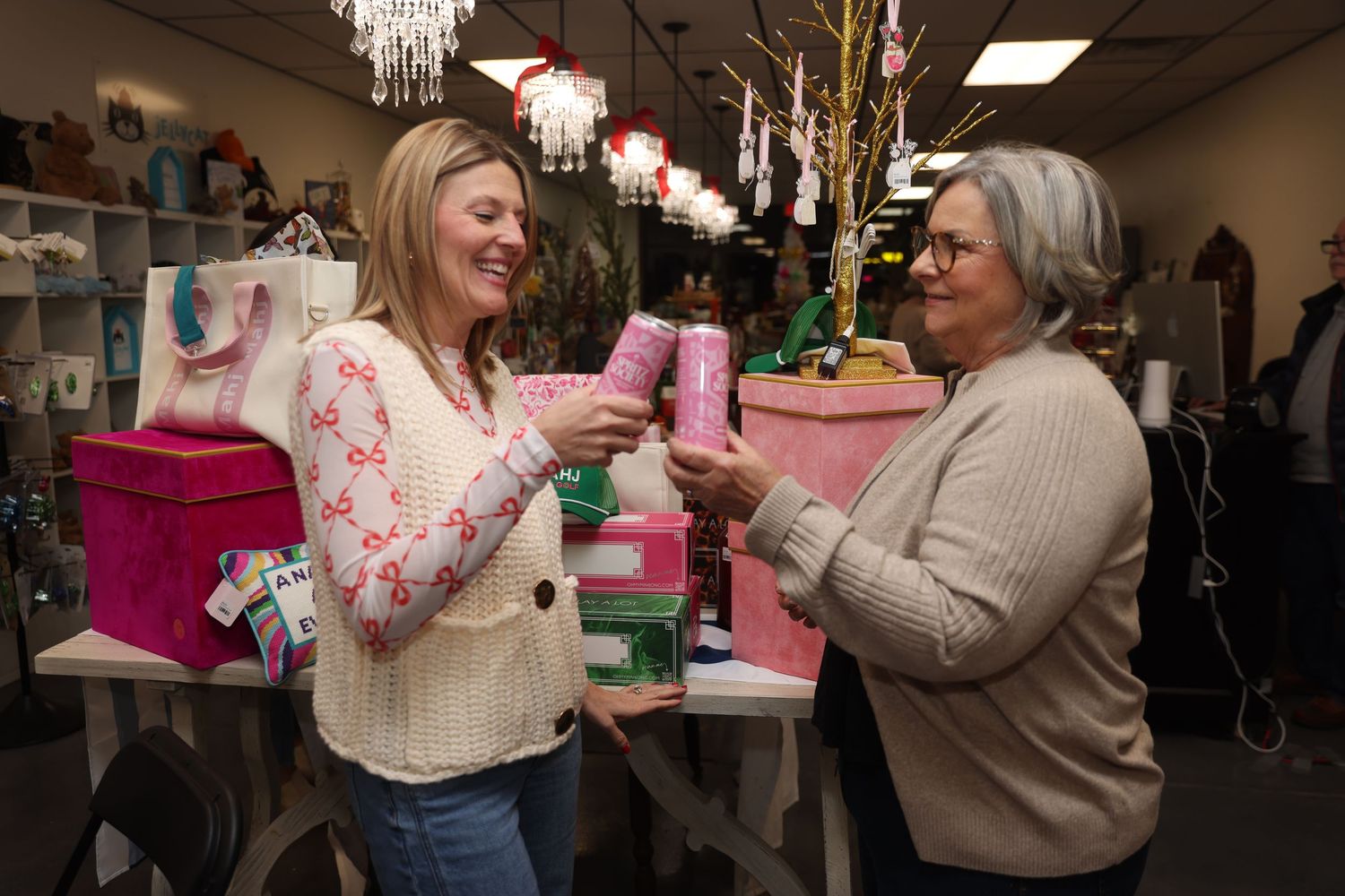 Two people share a laugh while enjoying drinks at a casual indoor gathering.