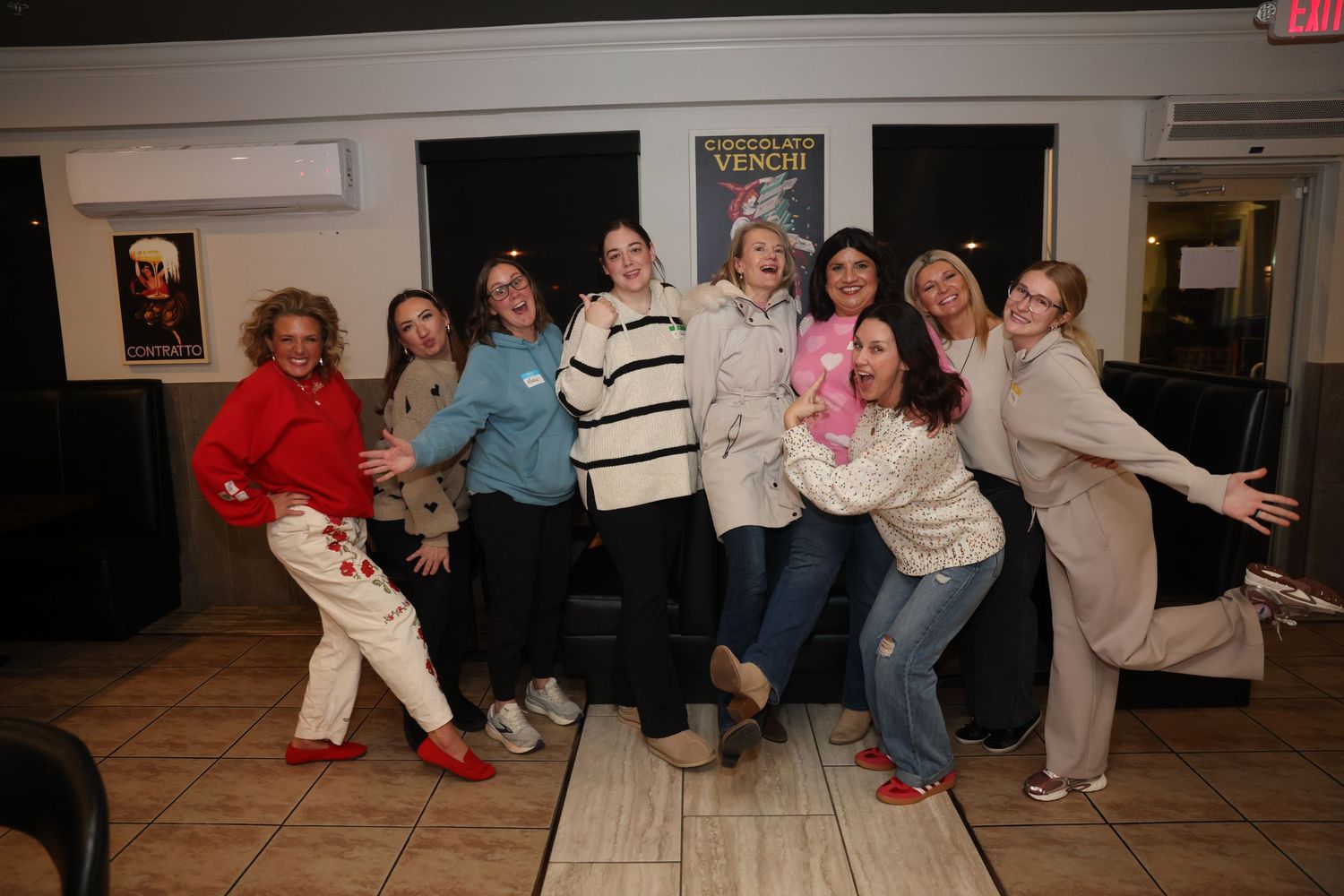 A group of people strike playful dance poses together in a casual indoor setting.