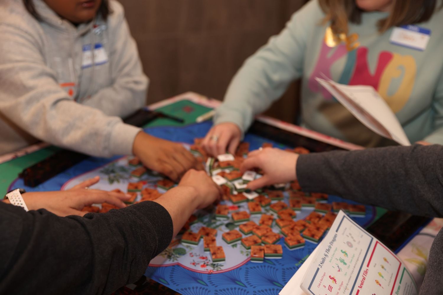 People working together to assemble a jigsaw puzzle on a blue table surface.