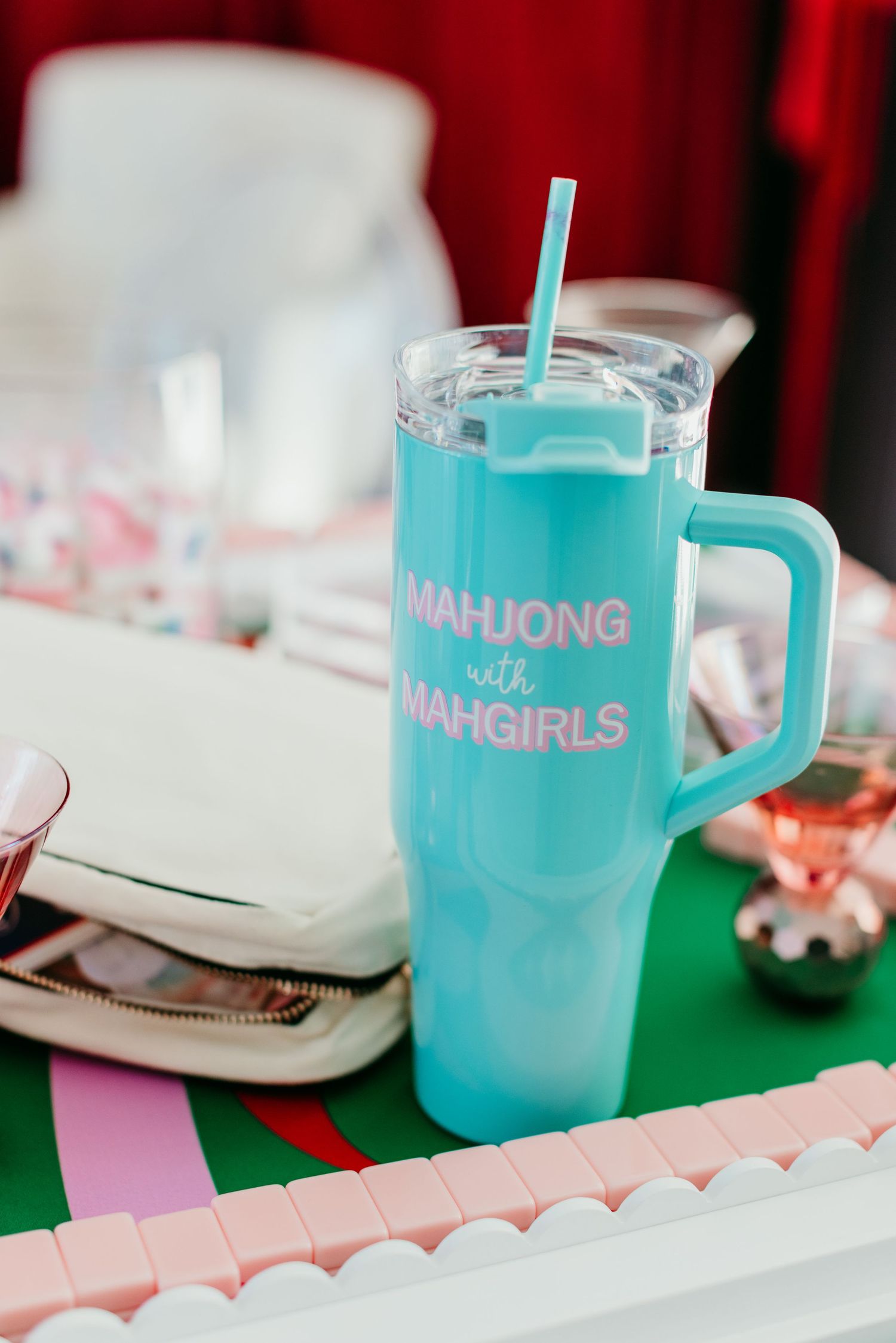 Turquoise blue mahjong-themed mugs with pink accents displayed on a white table setting.