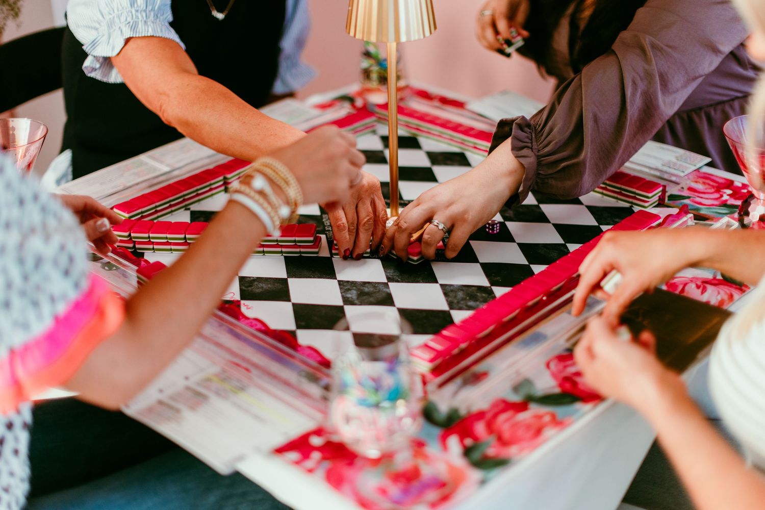 Close-up view of hands signing paperwork at a checkered table with red folders and documents spread out.