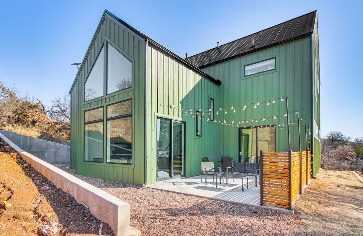 Row of green industrial buildings with modern architectural design against a desert landscape.