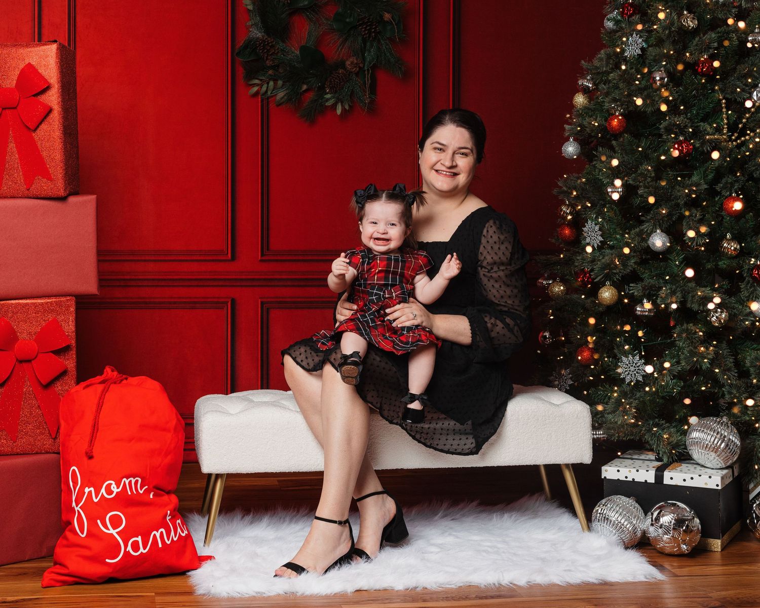 Holiday photo scene with Christmas tree, white bench, and red decorative elements.