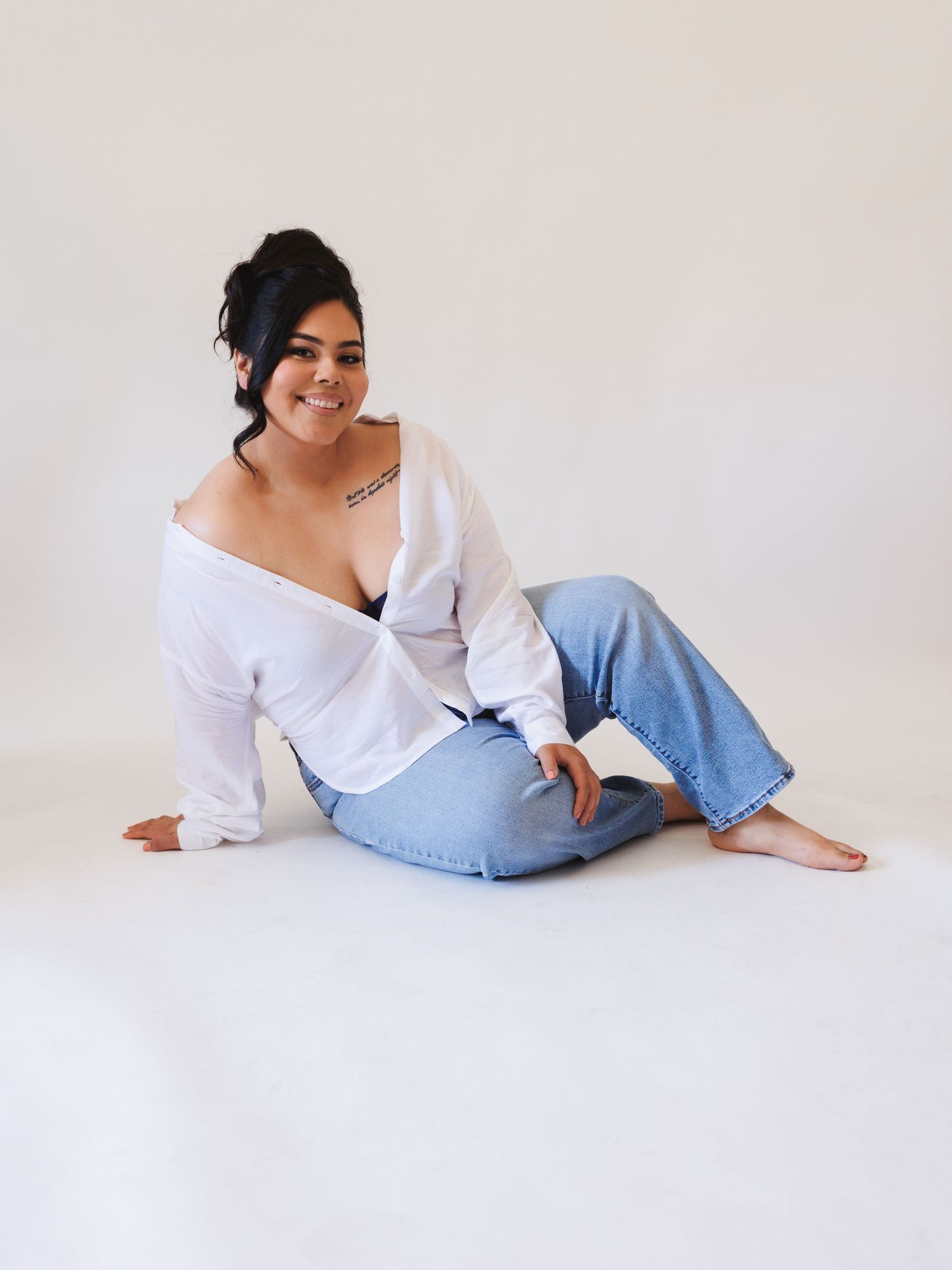 Person in white button-down shirt and jeans posing on white background.