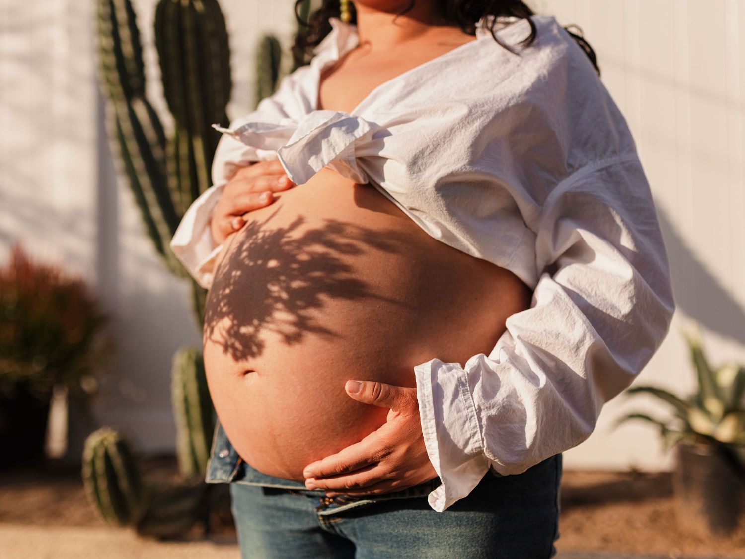 Close-up shots of a pregnant belly in white shirt against a sunlit backdrop.