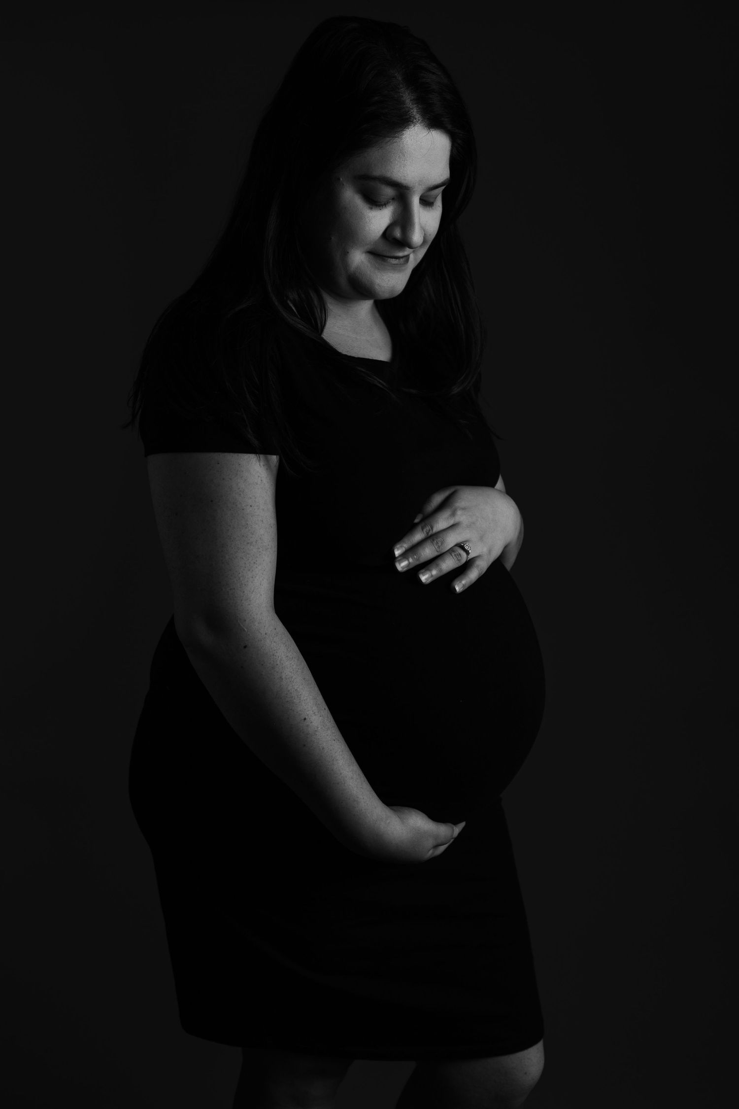 Intimate black and white maternity photography series with dramatic shadows.