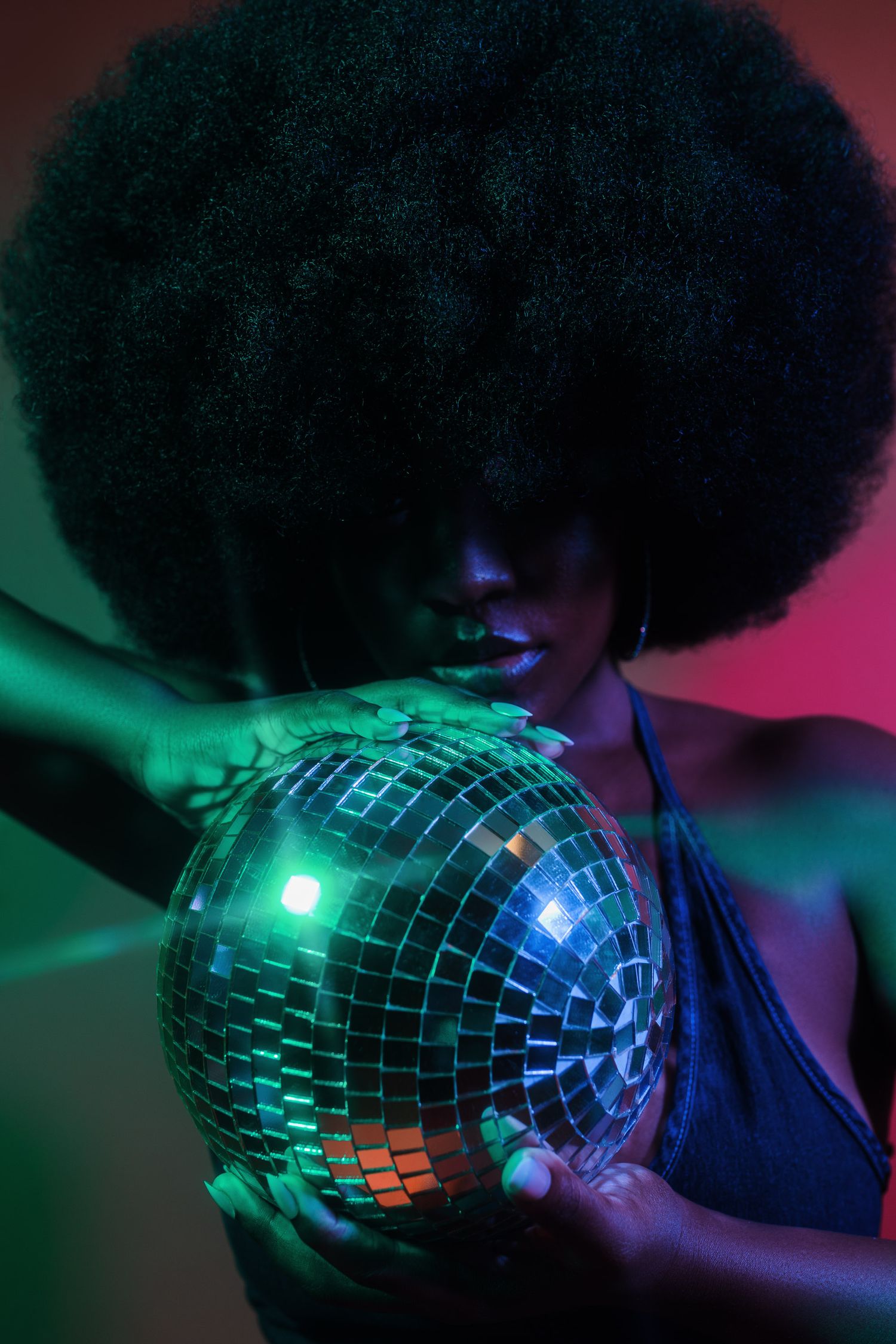 Close-up shot of disco ball reflecting colorful lights in dark setting.