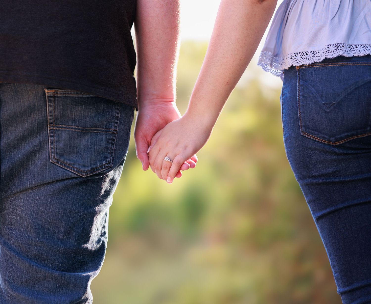 Close-up of denim jeans and casual footwear in a wooded outdoor setting.