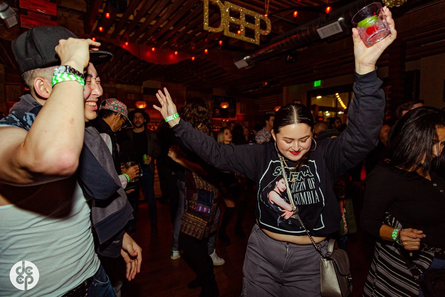 Energetic crowd dancing and celebrating at dimly lit nightclub.