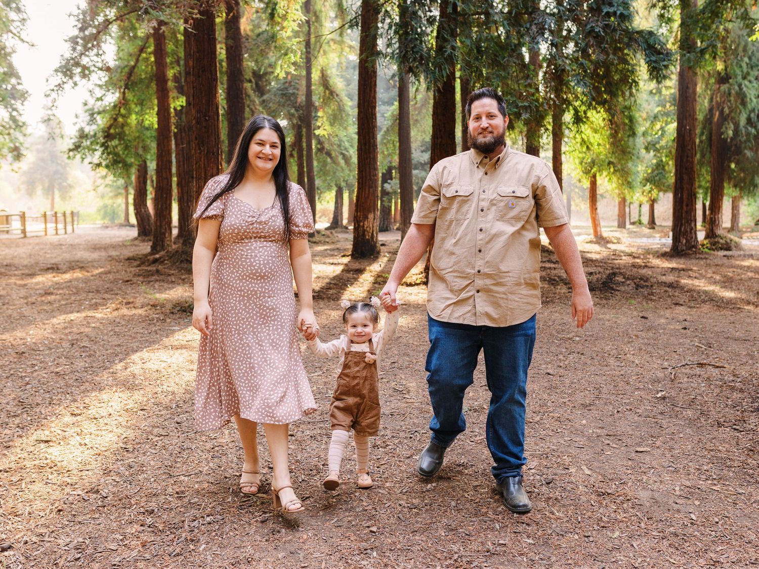Family walking together on a tree-lined path in casual attire.