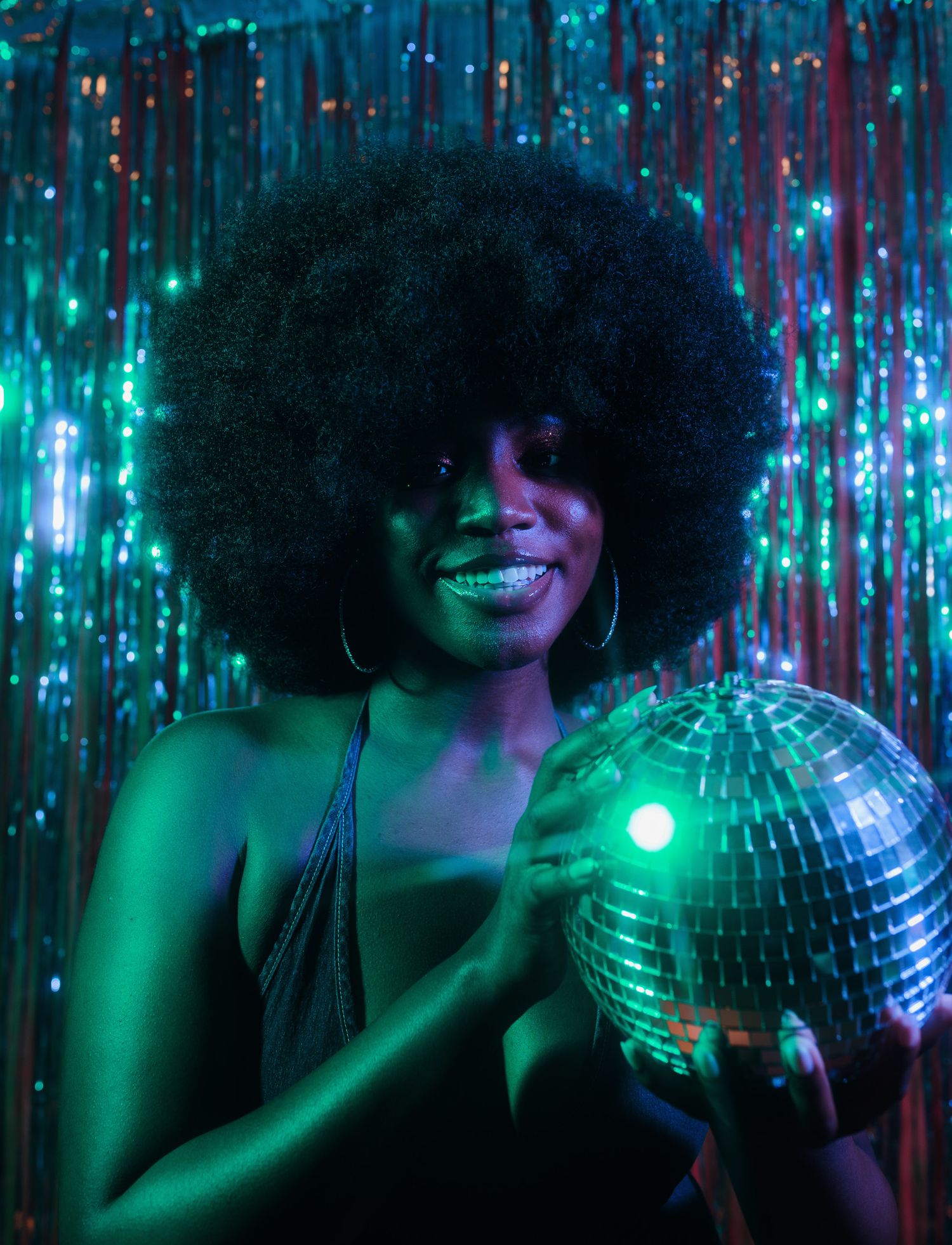 Disco portrait with glowing disco ball against shimmering backdrop in blue and purple lighting.