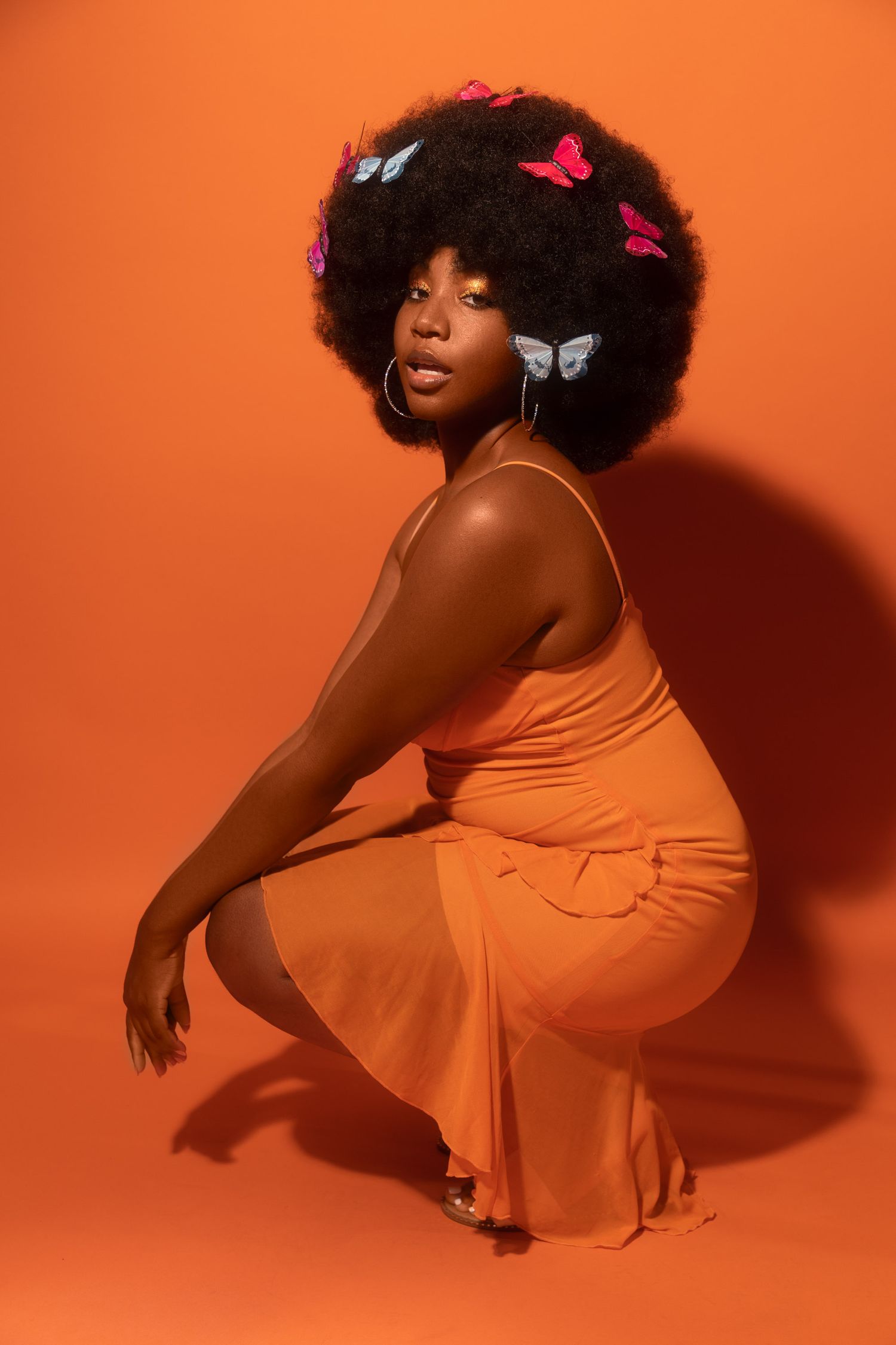Graceful pose in orange dress with butterfly accessories.