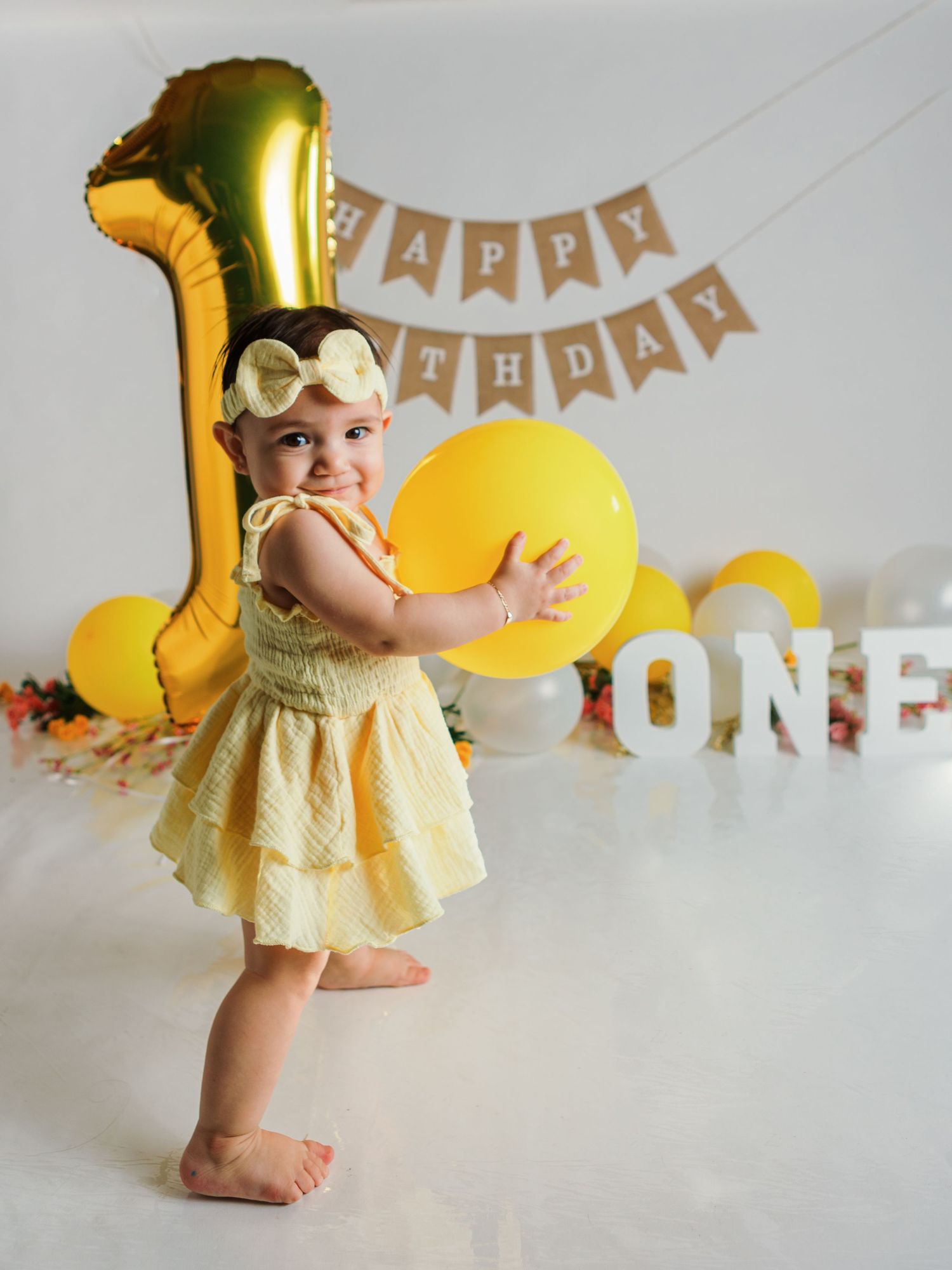 Birthday setup featuring gold number one balloon, yellow dress, and festive decorations.