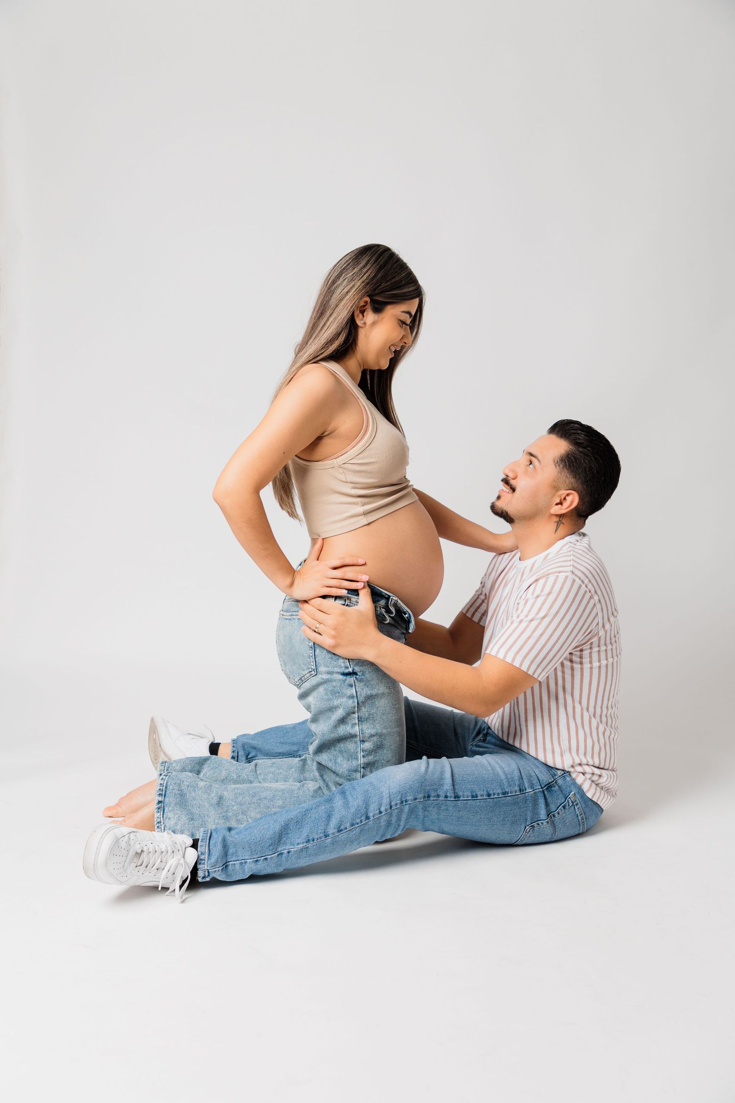Playful maternity photo showing couple's excitement about pregnancy on white backdrop.