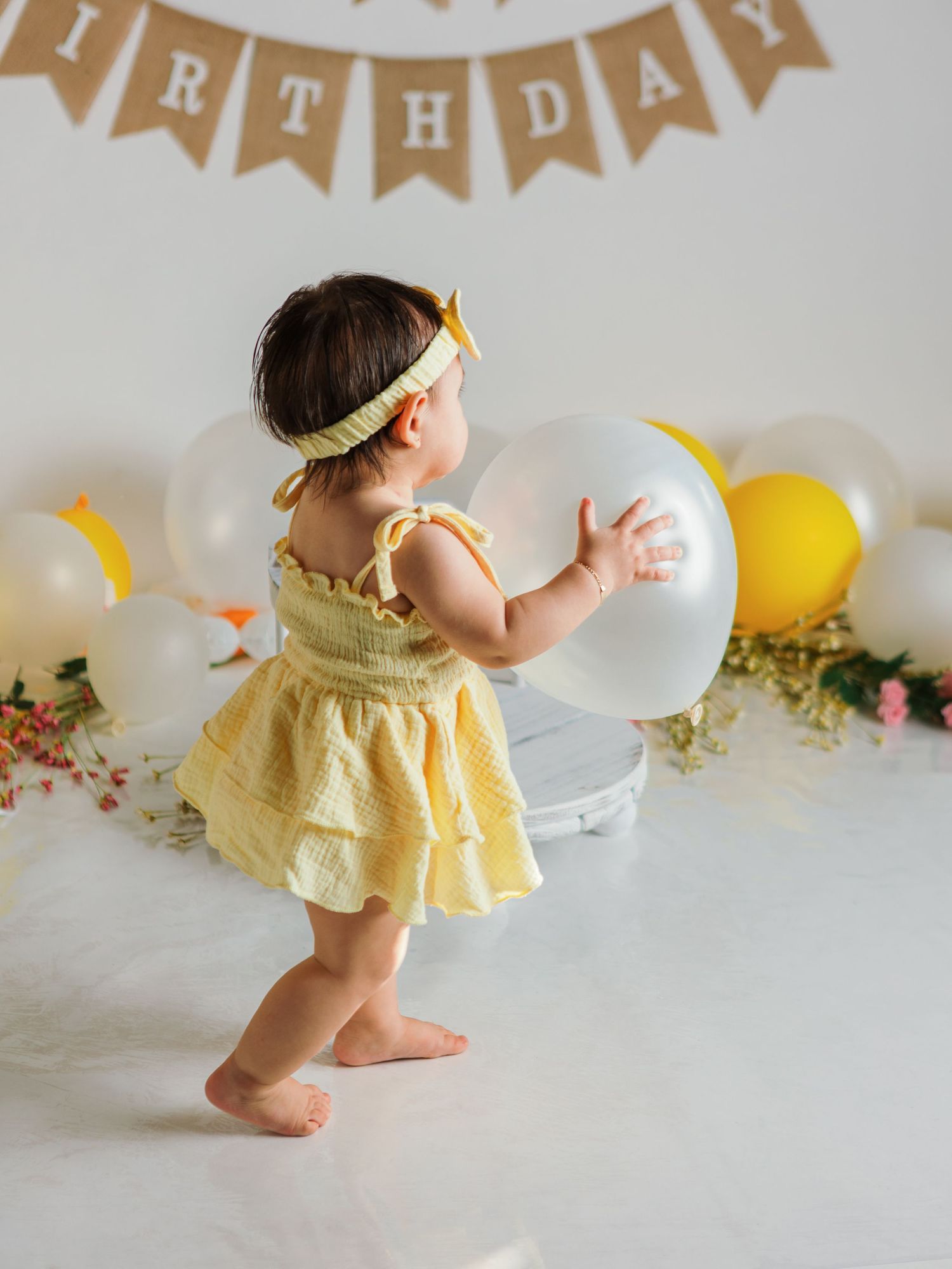 Yellow dress and party decorations with kraft paper happy birthday banner and balloons.