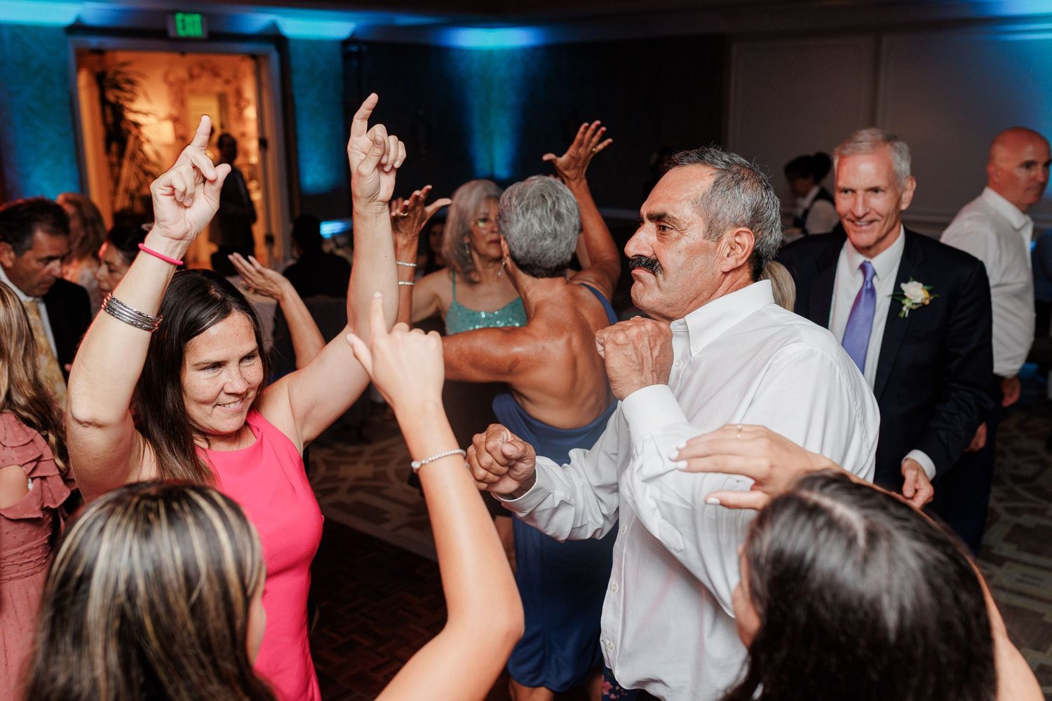 Energetic wedding guests dancing and celebrating on the dance floor at a lively reception.
