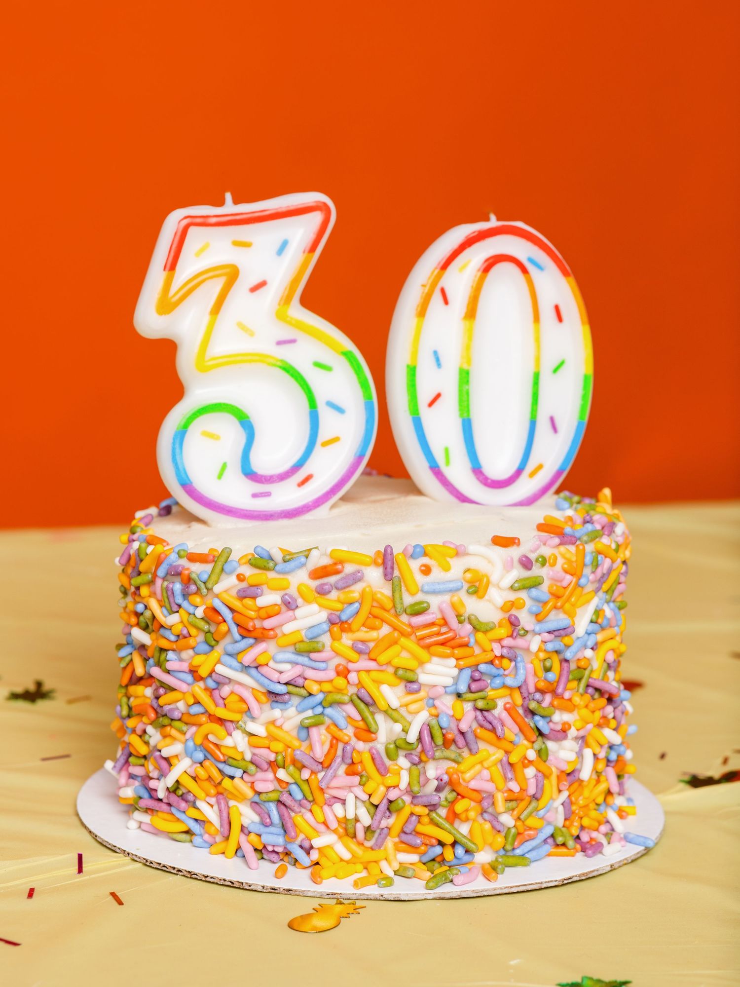 Birthday cake with number 50 candles and colorful sprinkles on wooden table.
