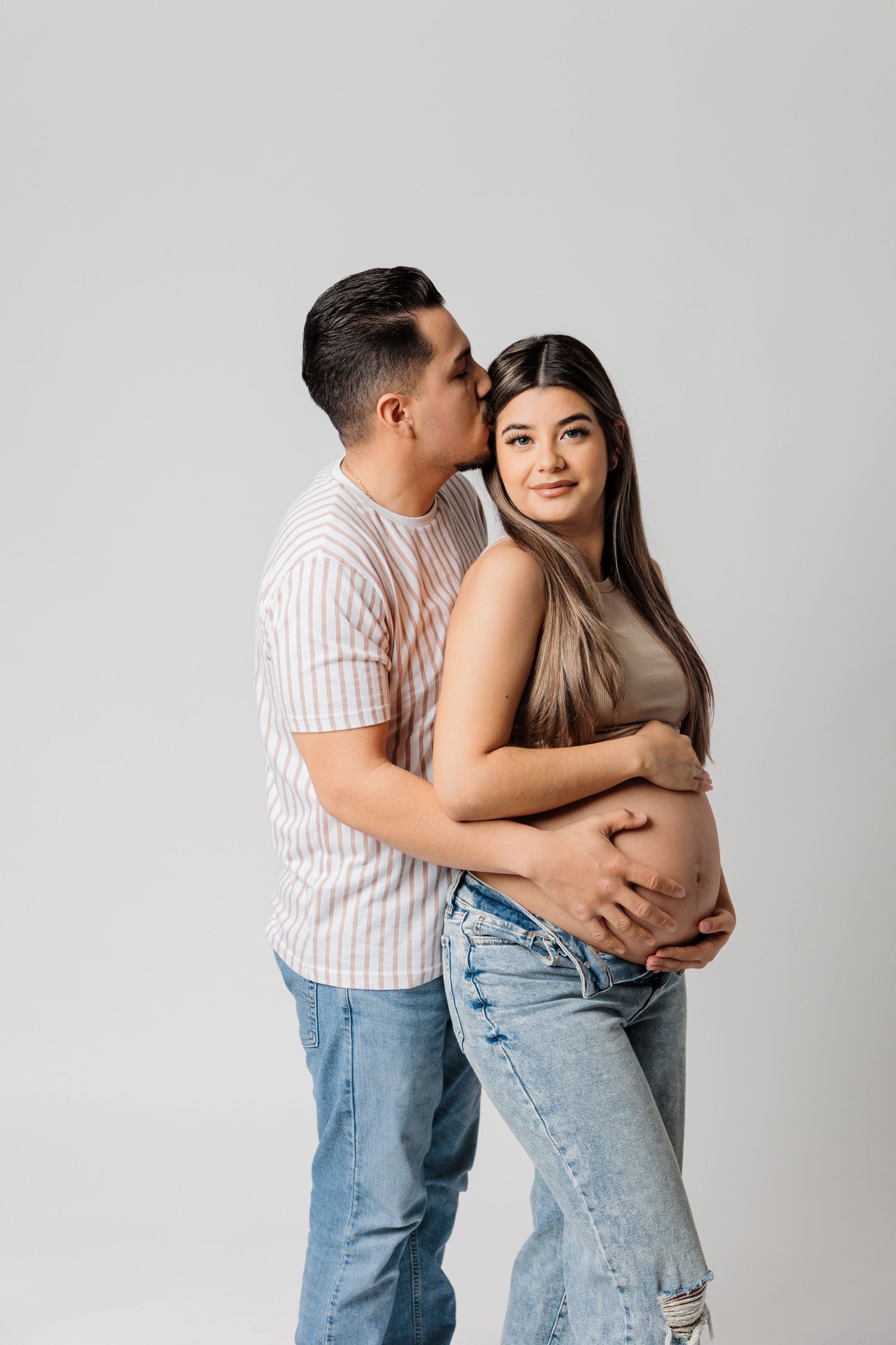 Intimate maternity portrait showing couple's connection against white background.