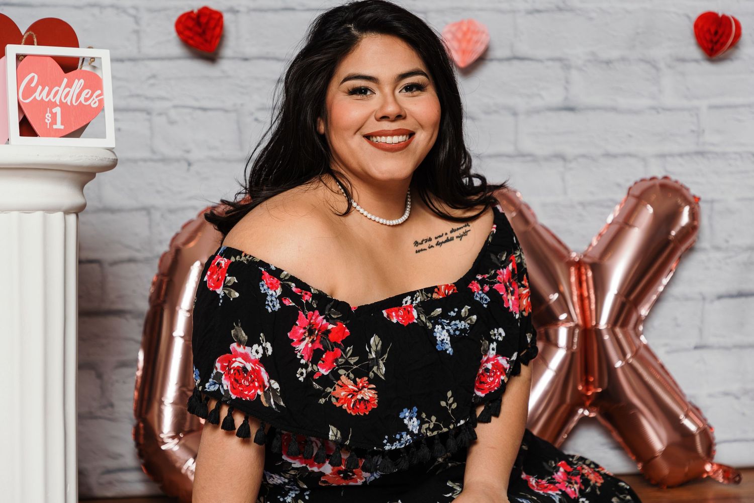 Valentine's day themed photoshoot setup with red hearts and decorative elements against white brick wall.