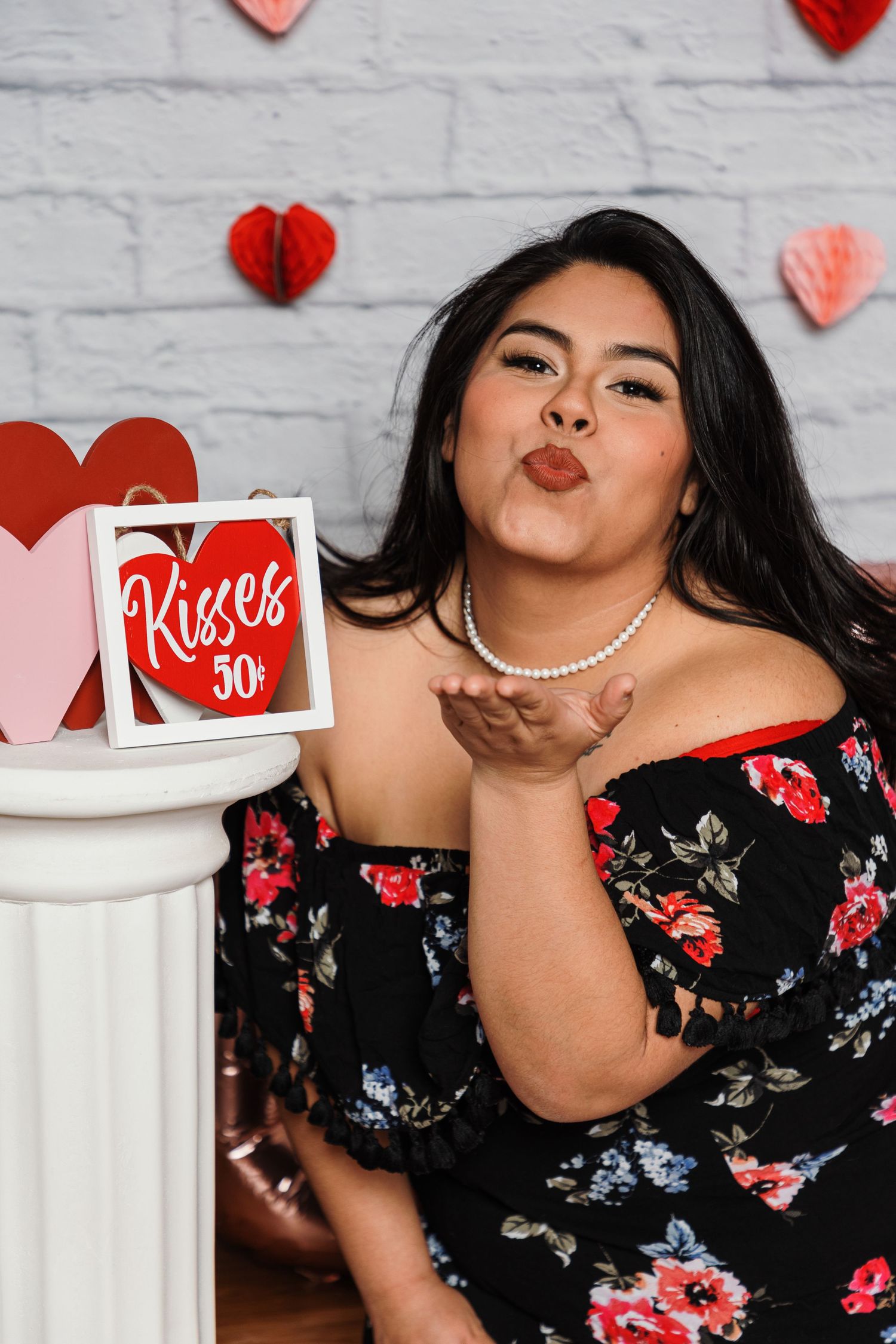 Floral dress against white brick wall with red and pink Valentine's hearts and decorative elements.