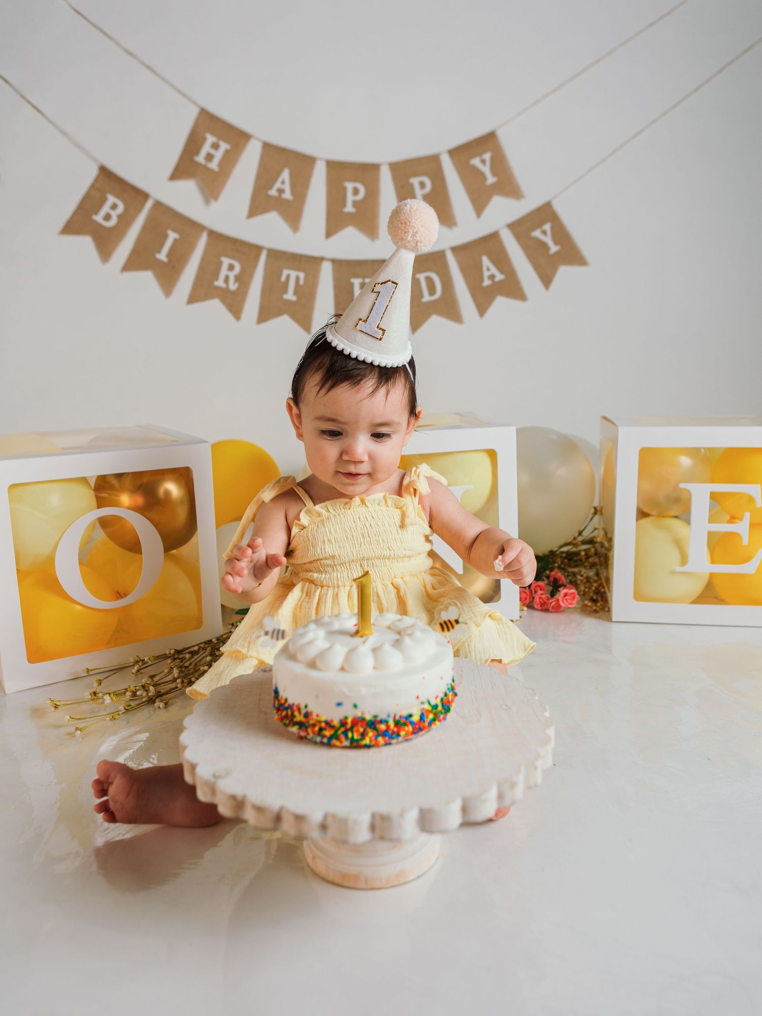 Birthday cake smash setup with white frosted cake and kraft paper banner decorations.