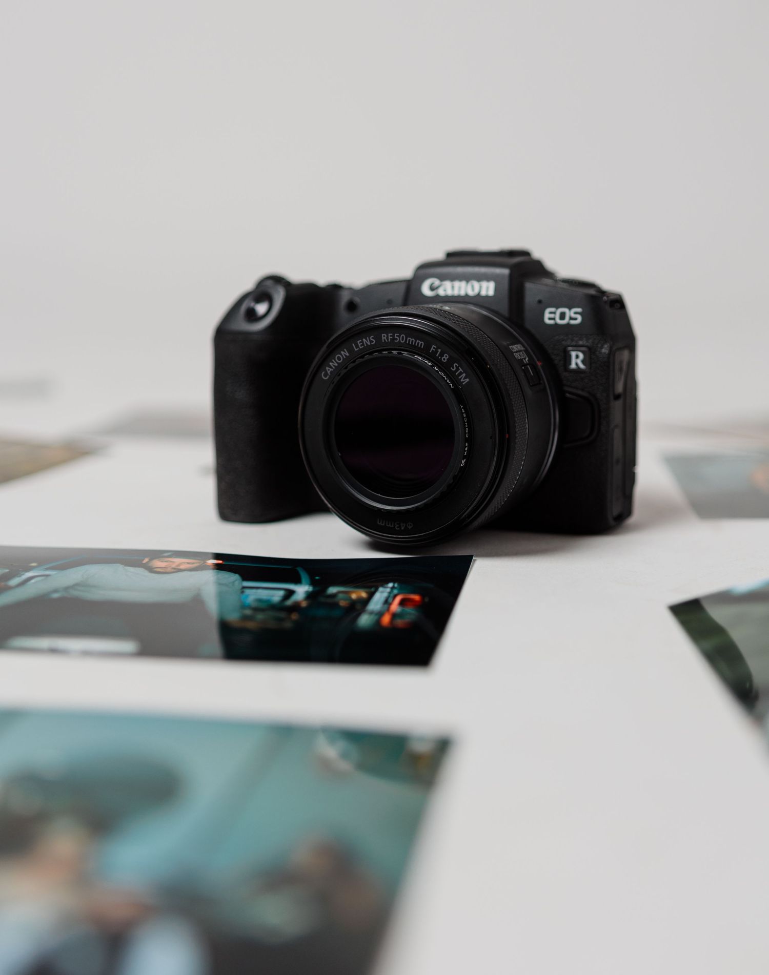 Canon EOS R mirrorless camera on scattered photos, perfect for professional photography and creative shoots.