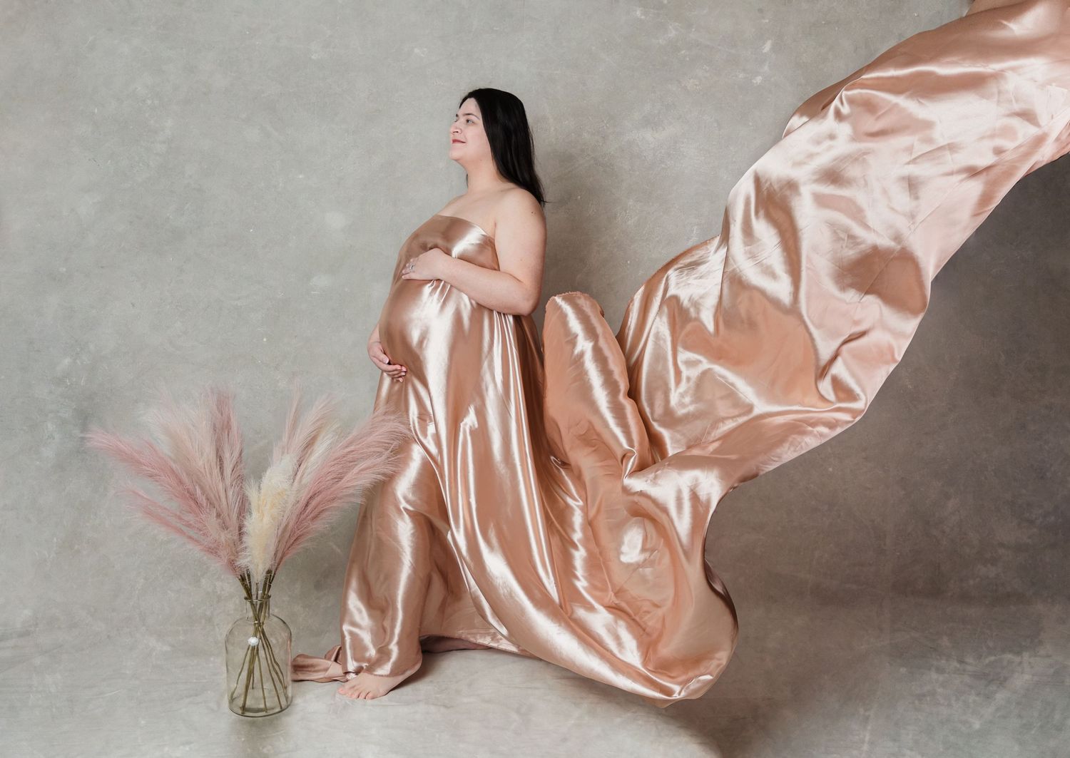 Shiny rose gold metallic fabric being draped and folded in multiple views against a gray background.