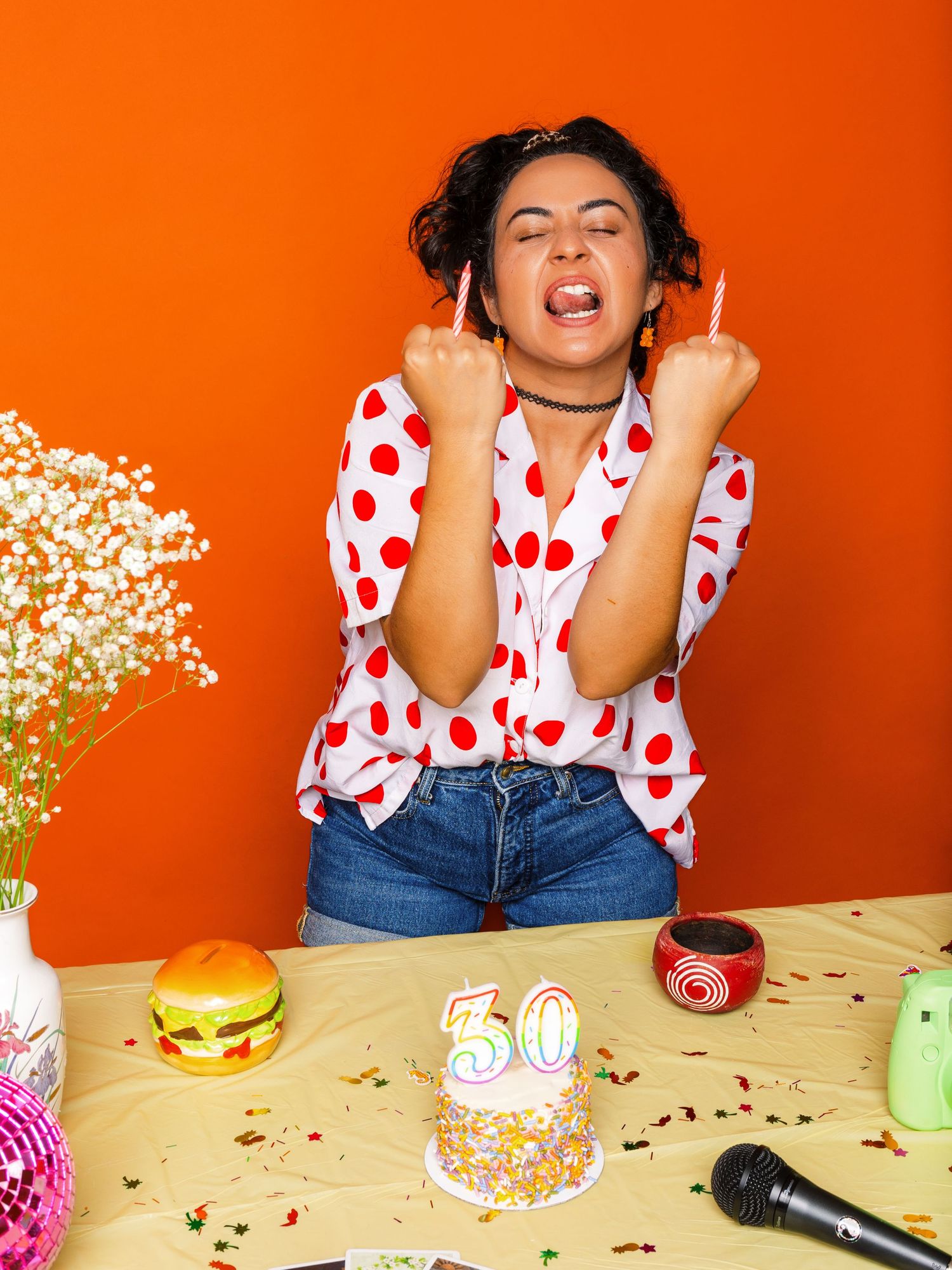 Party scene with cake, hamburger, and decorative elements on yellow table.