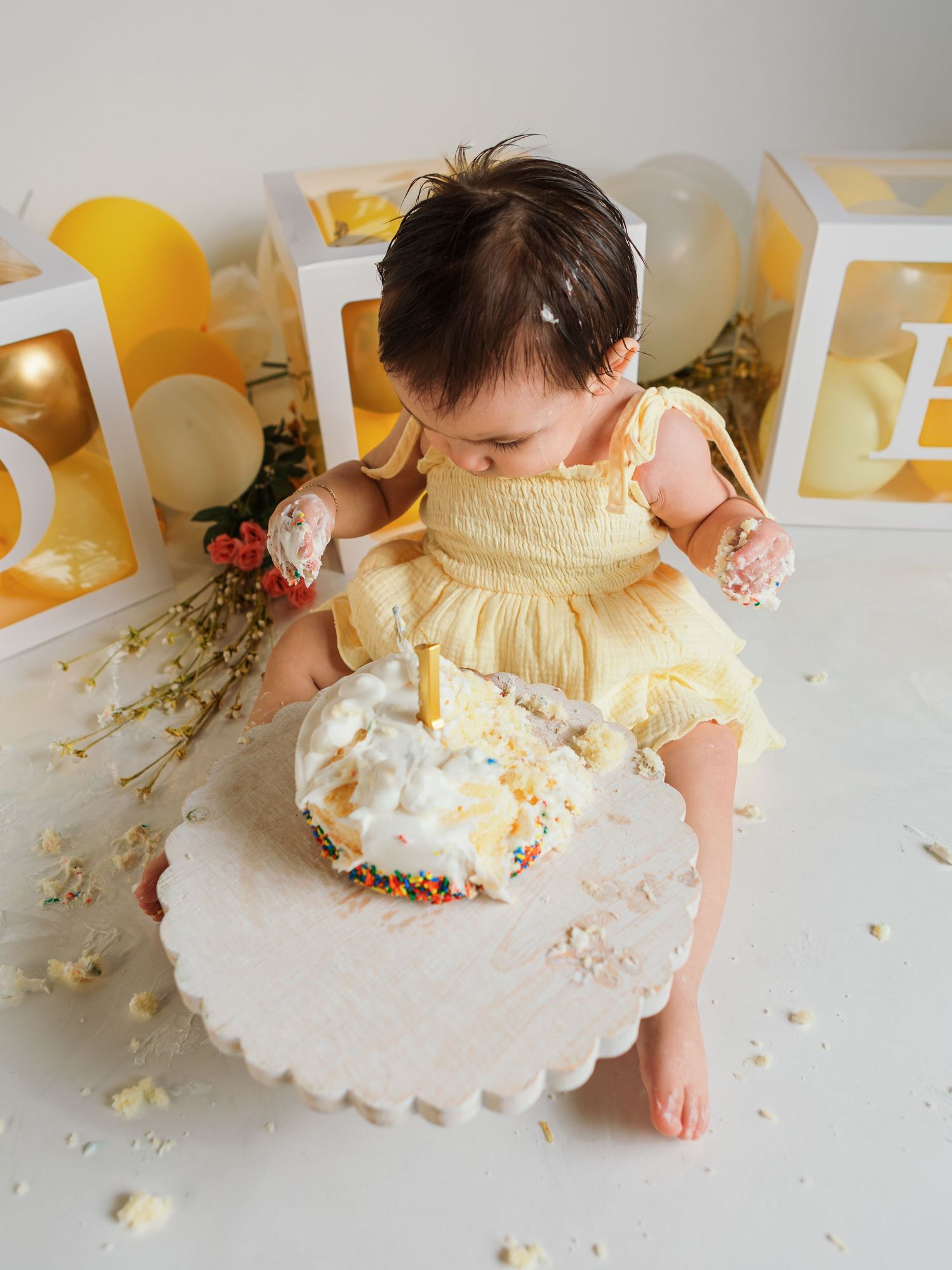 Cake smash aftermath with scattered frosting and yellow party decorations.