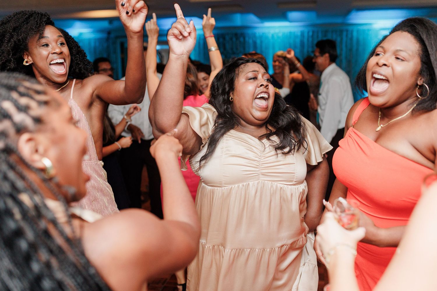 Women dance and celebrate joyfully on the dance floor at a wedding reception.