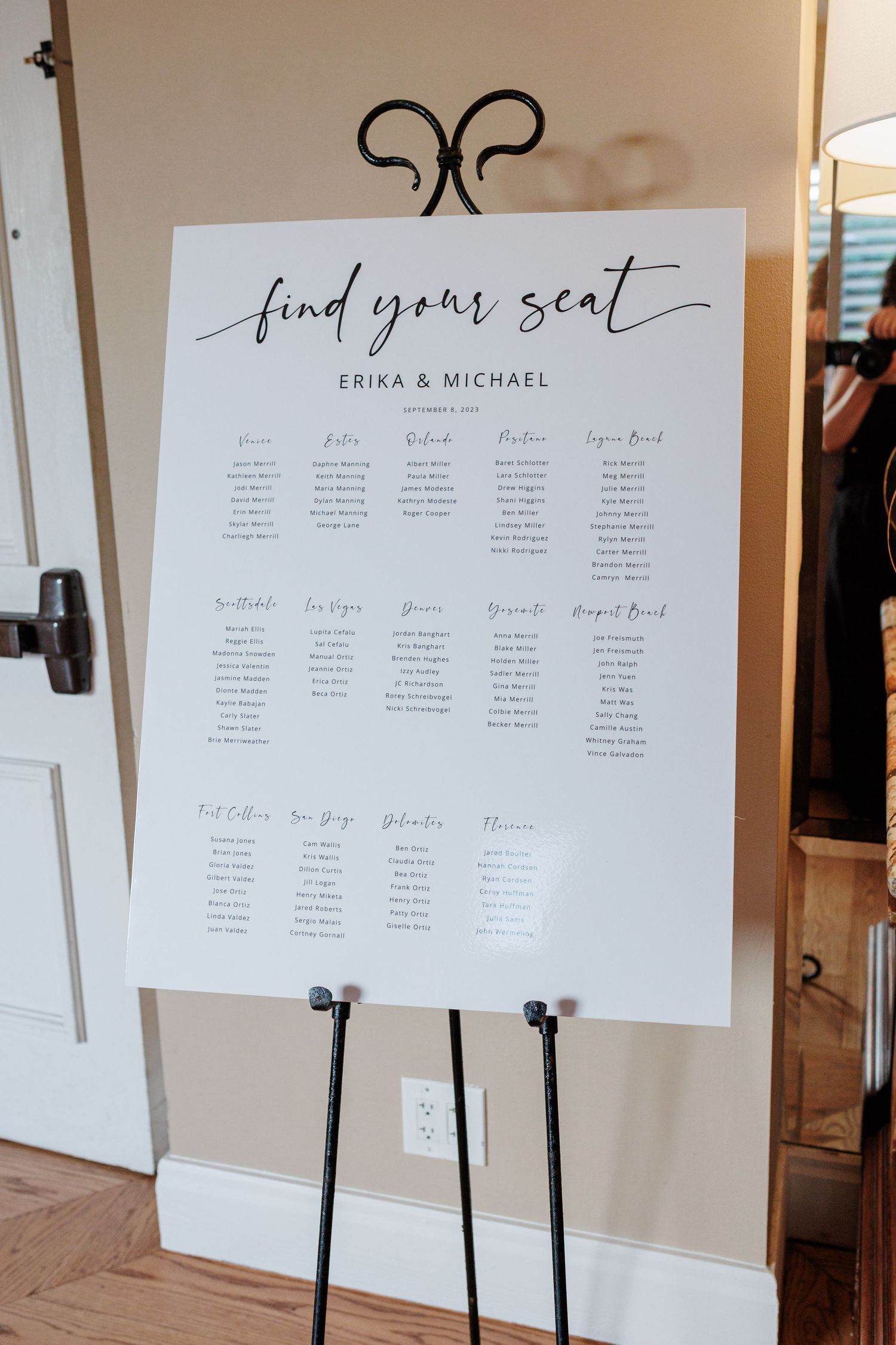 Elegant wedding seating chart on easel reading find your seat for Erika and Michael with guest table assignments.