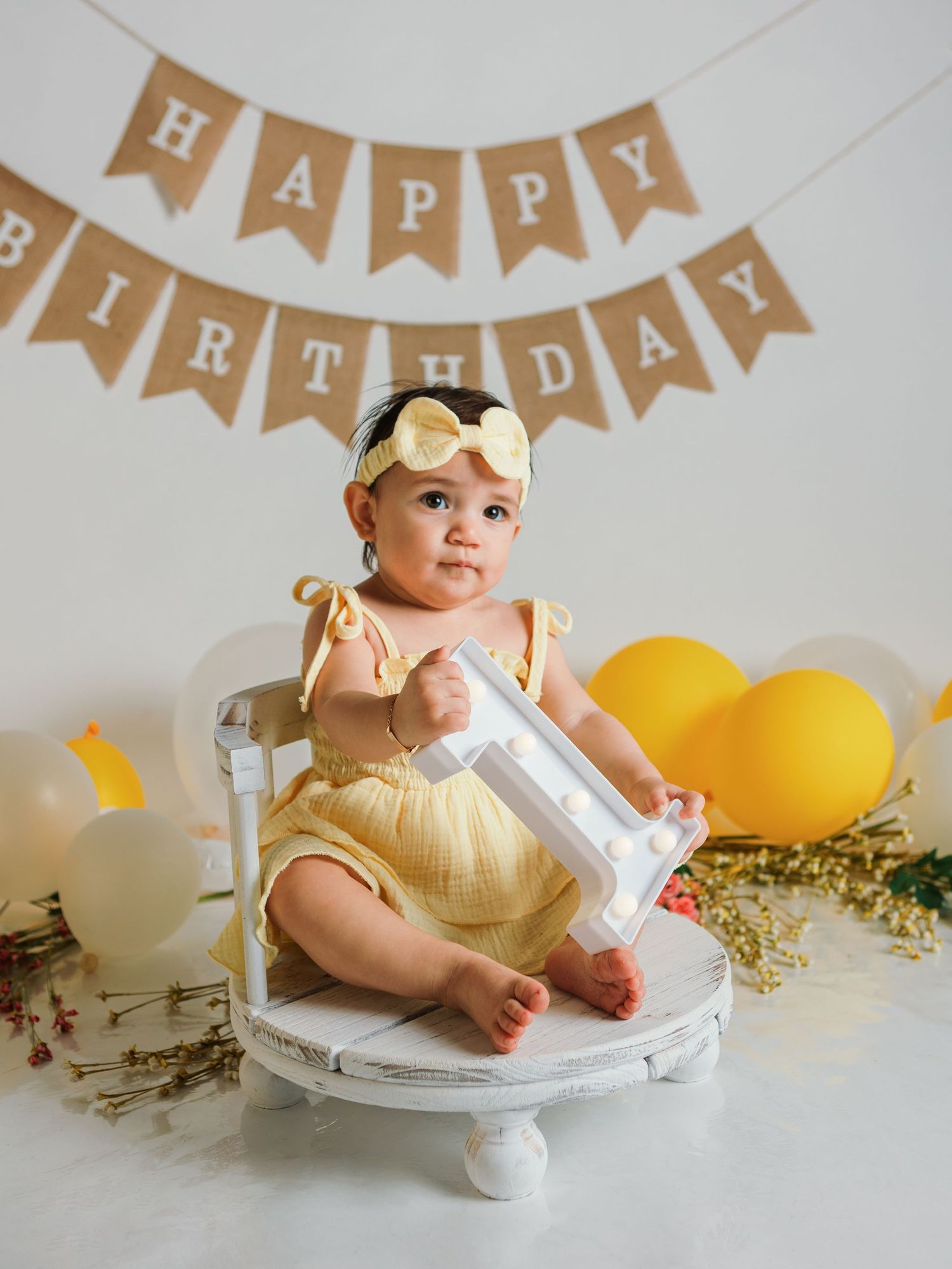 Birthday party scene with rustic banner decorations and yellow balloons against white backdrop.