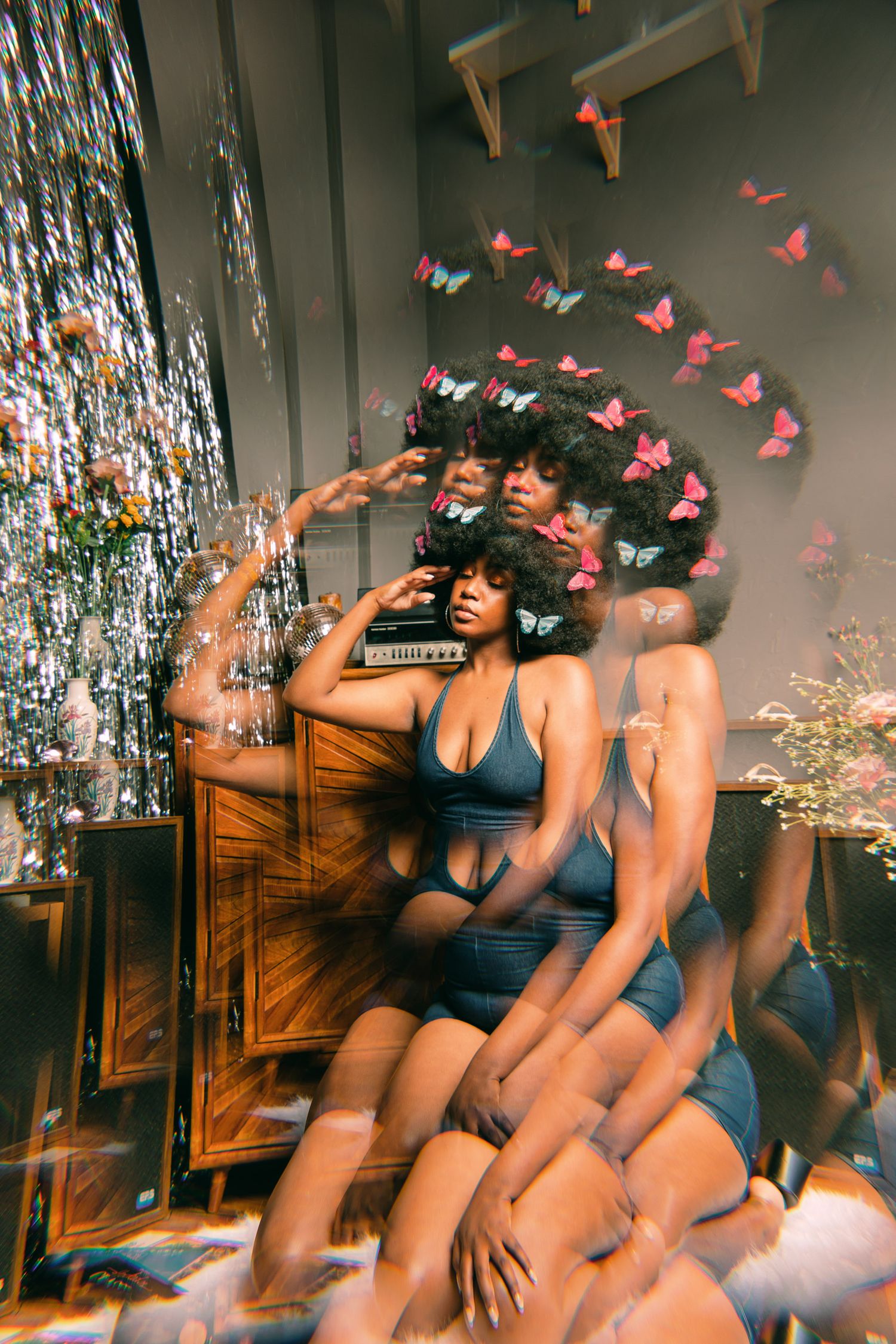 Artistic boudoir photoshoot with pink butterfly decorations and silver tinsel backdrop.
