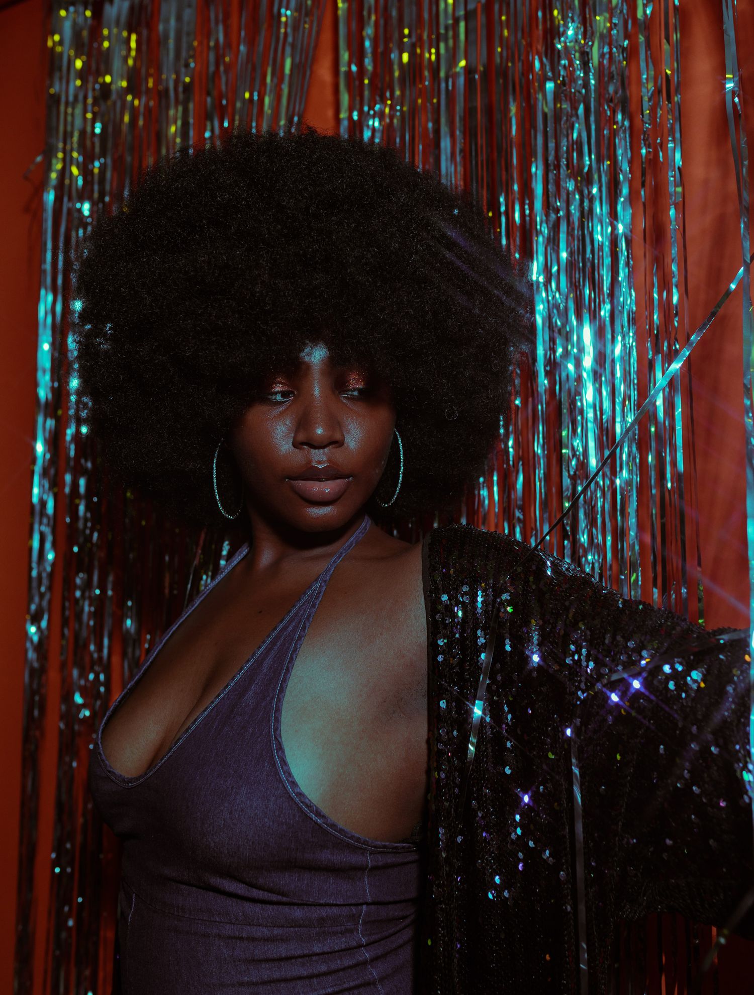 Studio portrait with natural lighting against sparkly tinsel backdrop.