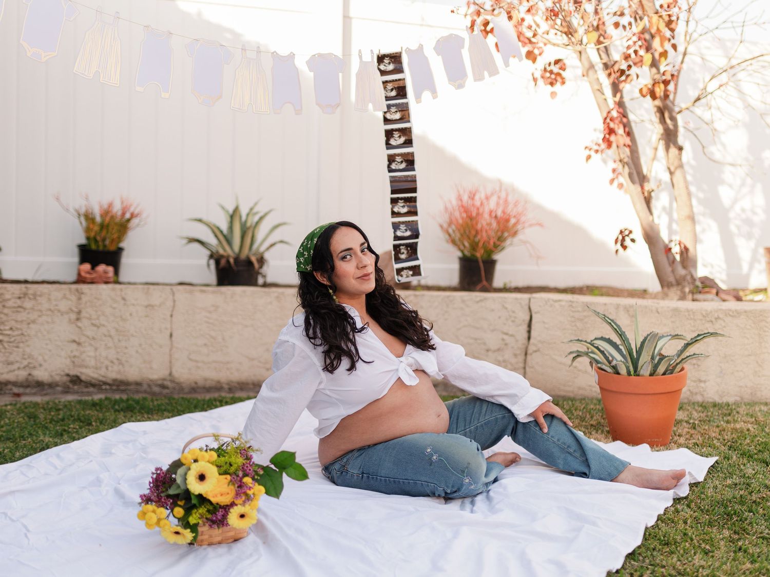 Outdoor photoshoot setup with white blanket and floral arrangements at sunset.