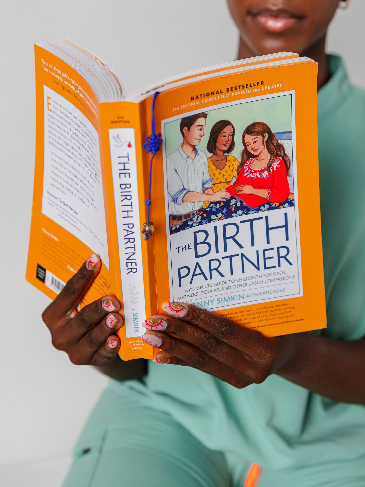 Orange book titled 'The Birth Partner' held open against white background.