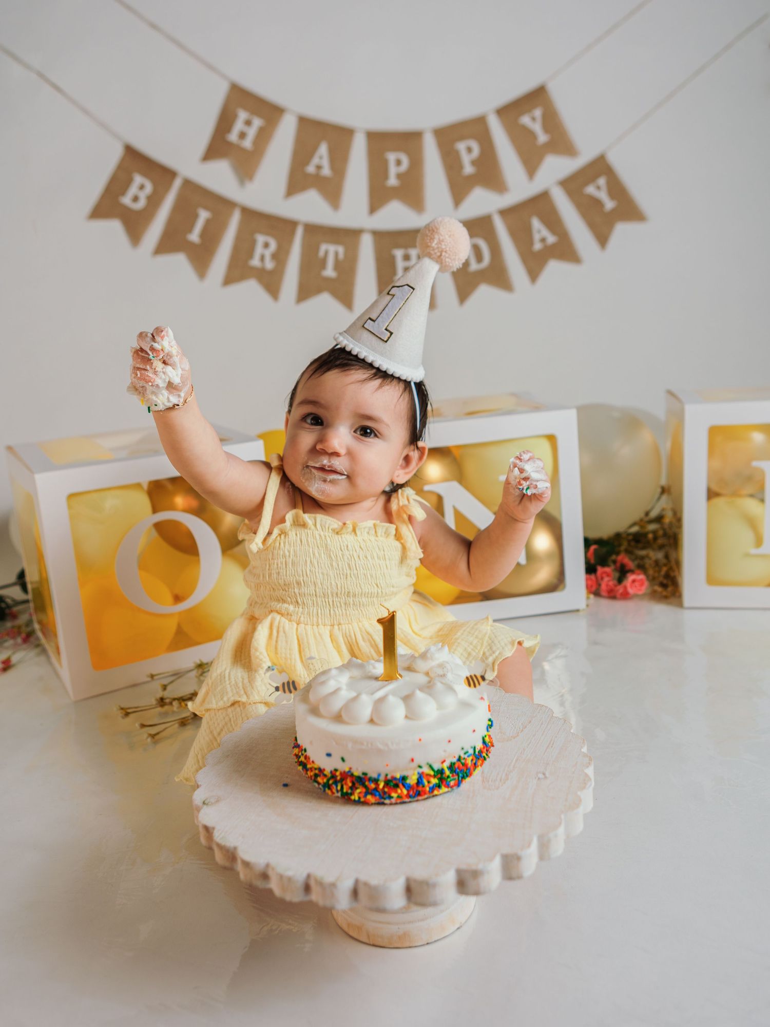 First birthday cake smash scene with white frosted cake and festive decorations.